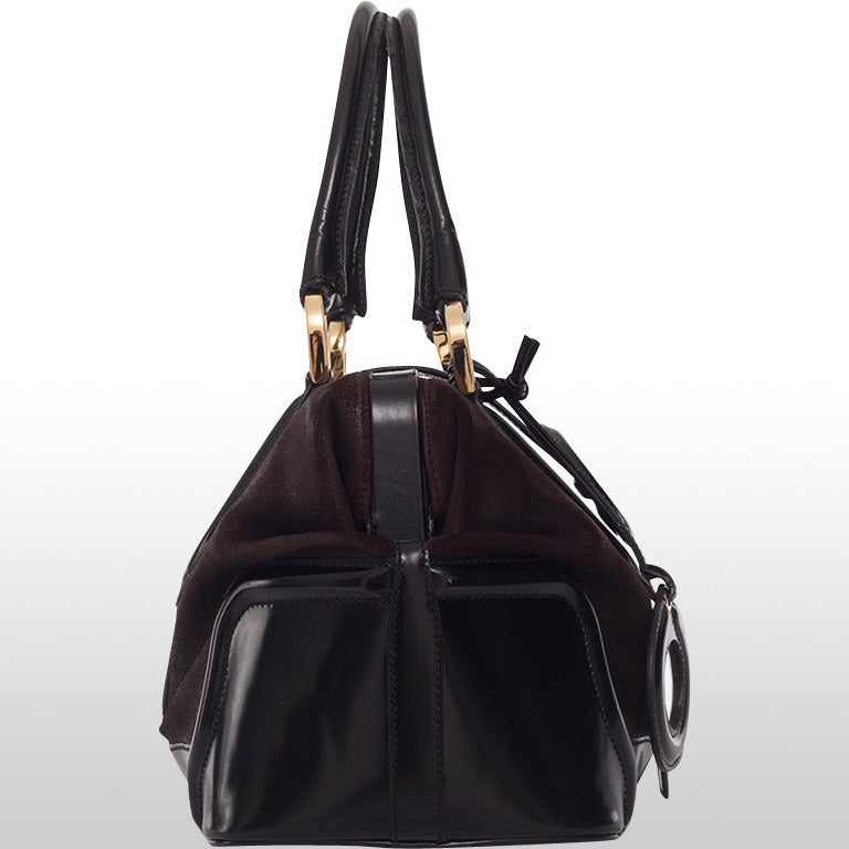 A perfect day bag that is chic and distinctive as well as utilitarian. The main body of the bag is made in a chocolate brown suede and it is trimmed in a fine black patent leather. The bag features a small cosmetic mirror also trimmed in black