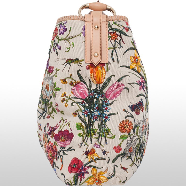This is a beautiful large hobo bag with a flora motive featuring sparkling rhinestone details dotted throughout the print. The sturdy canvas is also signed 'Gucci' in several places. The bag features the classic horsebit natural leather handle and