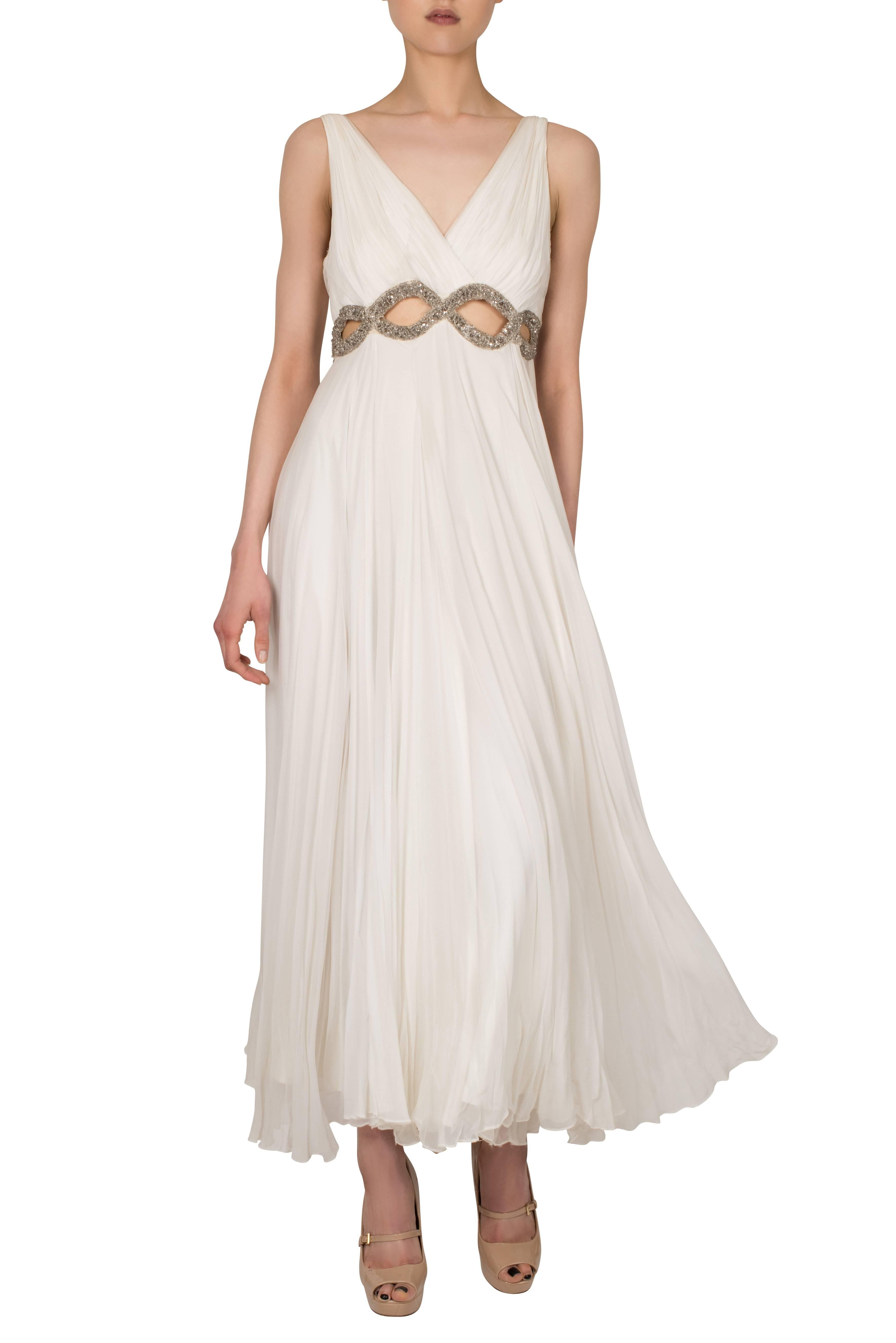 This is a beautiful 1960's grecian style gown. The dress is made out of a creamy white chiffon fabric, draped around the bosom and gathers by the waist, which make the dress fall beautifully. Under the bosom there are oval shaped cut outs, decorated