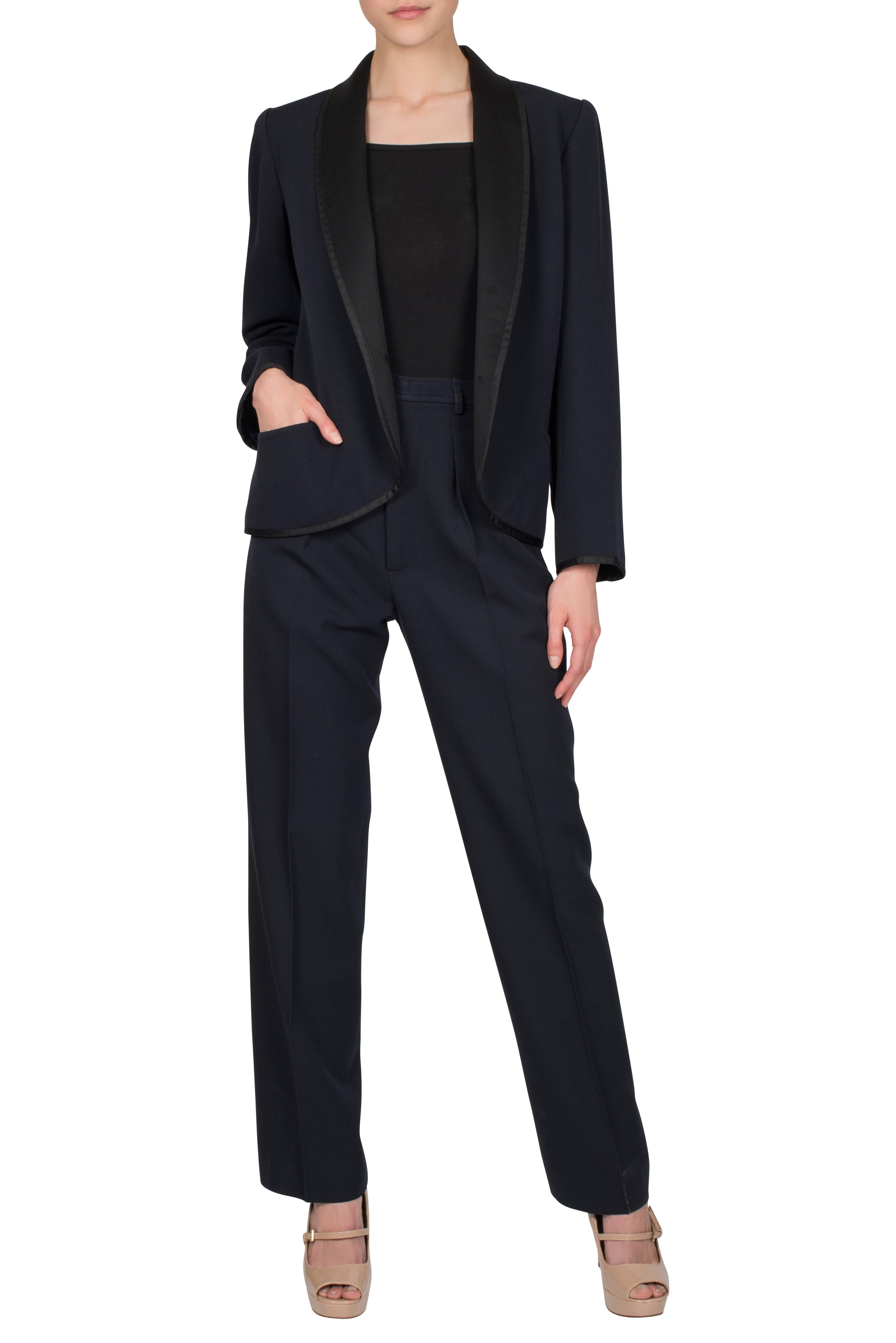 A late 1970's Yves Saint Laurent Rive Gauche navy blue wool ‘Le Smoking’ trouser suit with black silk lapels. The tailored navy blue wool jacket features two hip pockets, lightly padded shoulders and bracelet-length sleeves with buttons and a black