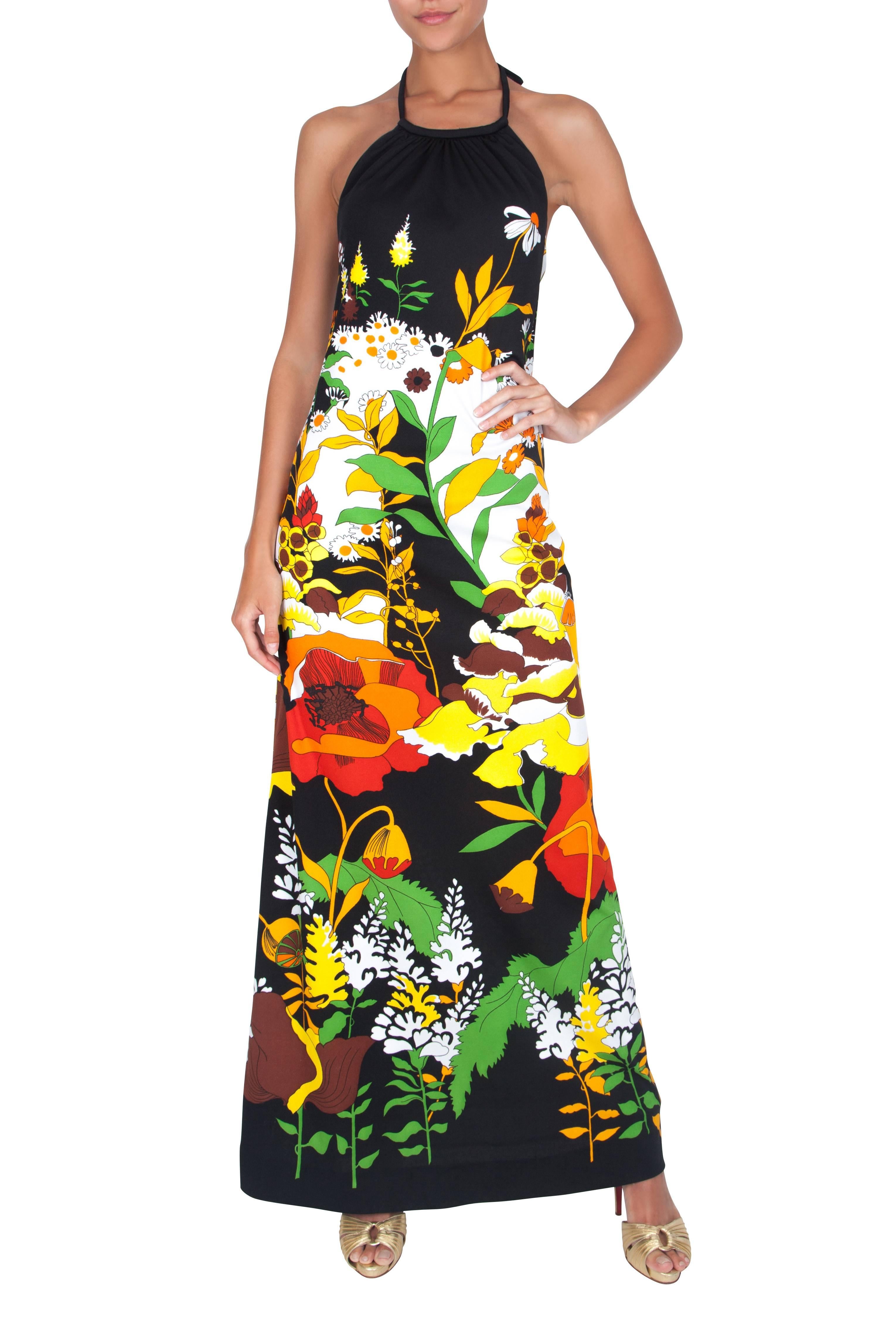 The focal point in this 1970's black halter dress is the striking placement print in white, orange and green. Made from a black lightweight synthetic fabric, extremely soft to the touch. This dress is unlined and features a halter shape with a