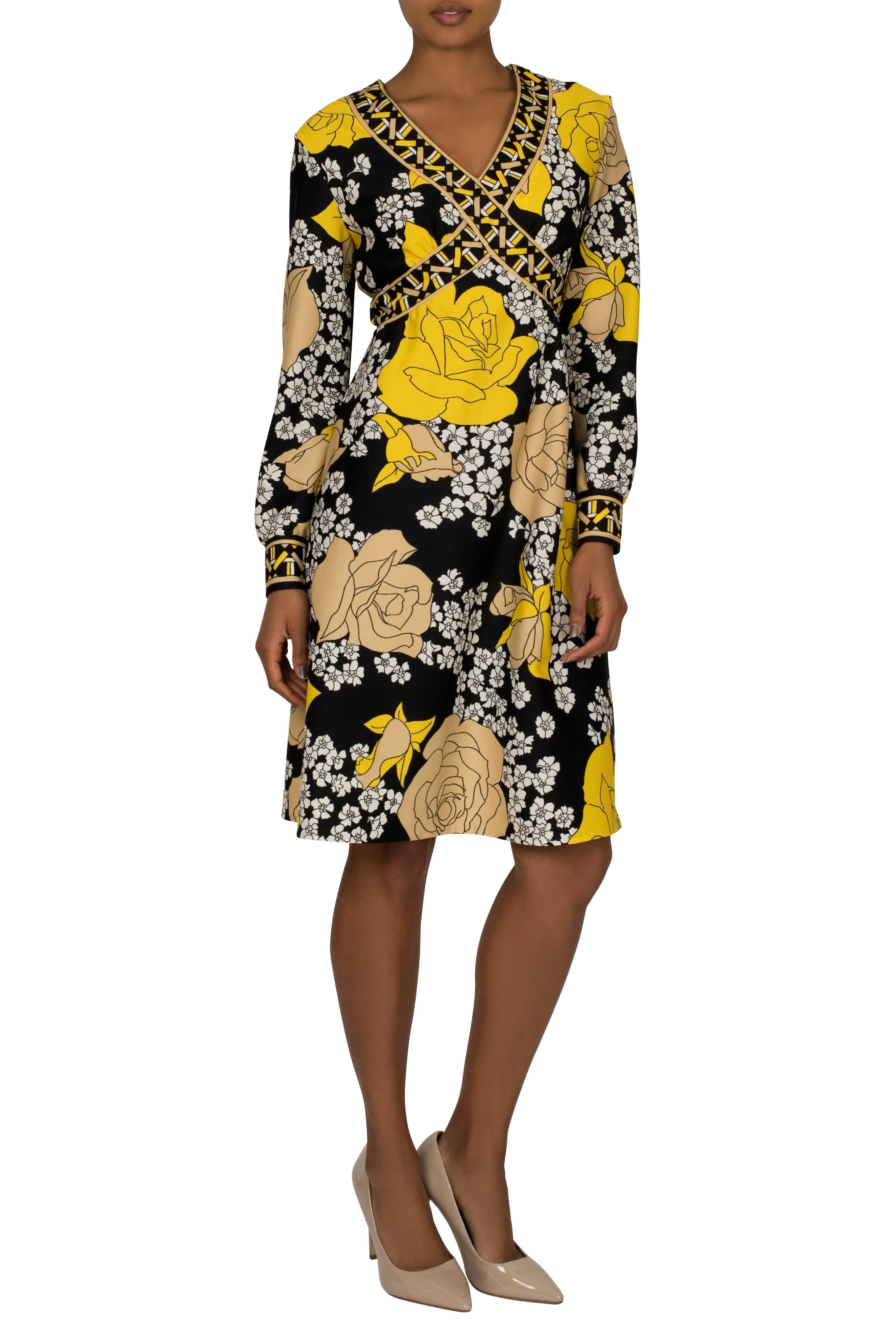 A 1970's yellow and black geometric floral mini dress by Nancy Valentine. The flattering decolletage is adorned with a band featuring a Greek frieze pattern, which crosses under the bust and encircles the back. It has full length puffed sleeves and