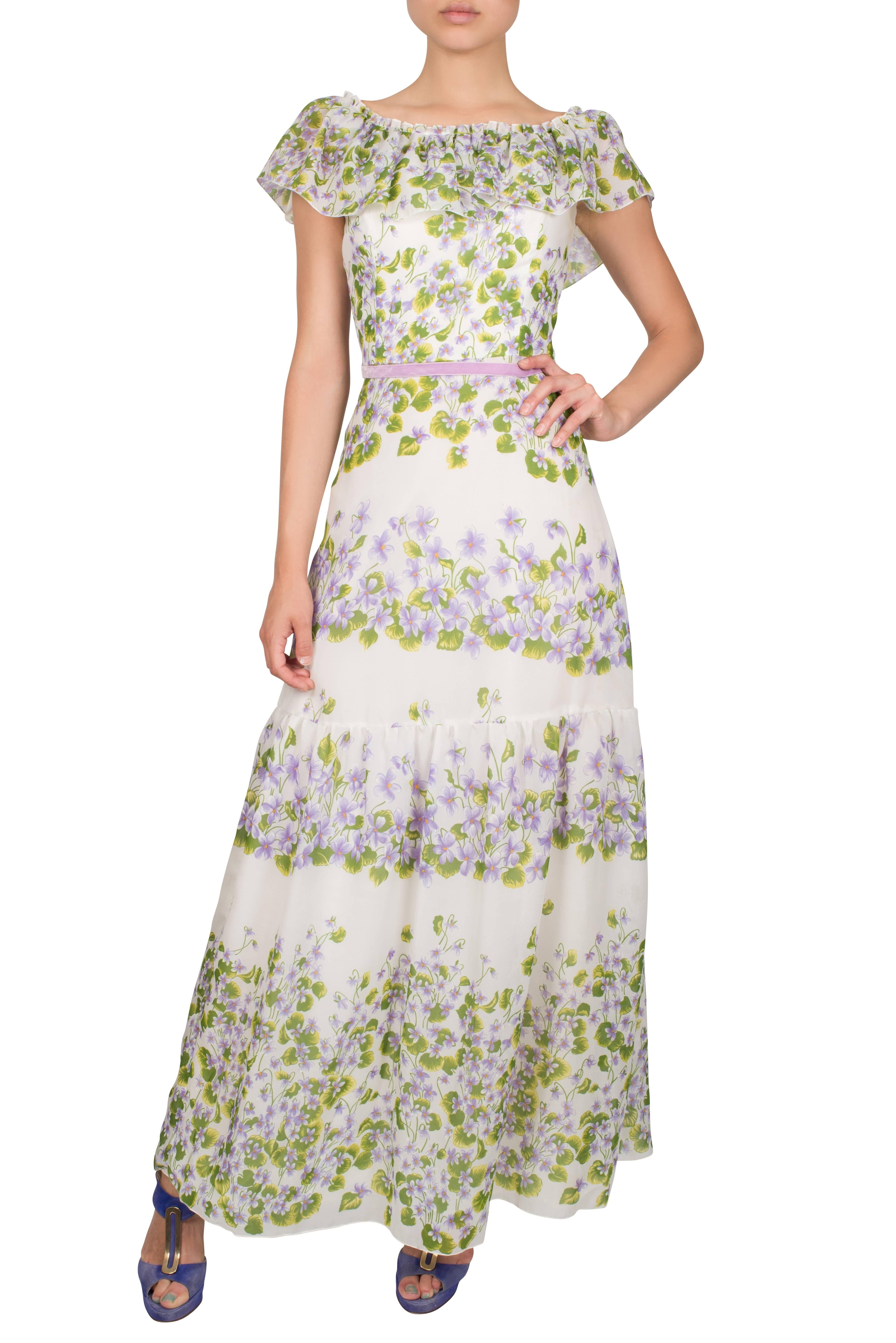 Romantic 1970's tiered off-the-shoulder dress in a soft lavender and green floral pattern. This beautiful dress features a ruffled collar which sits beautifully over the shoulder and a fitted waist that ties up with a thin lavender velvet ribbon.