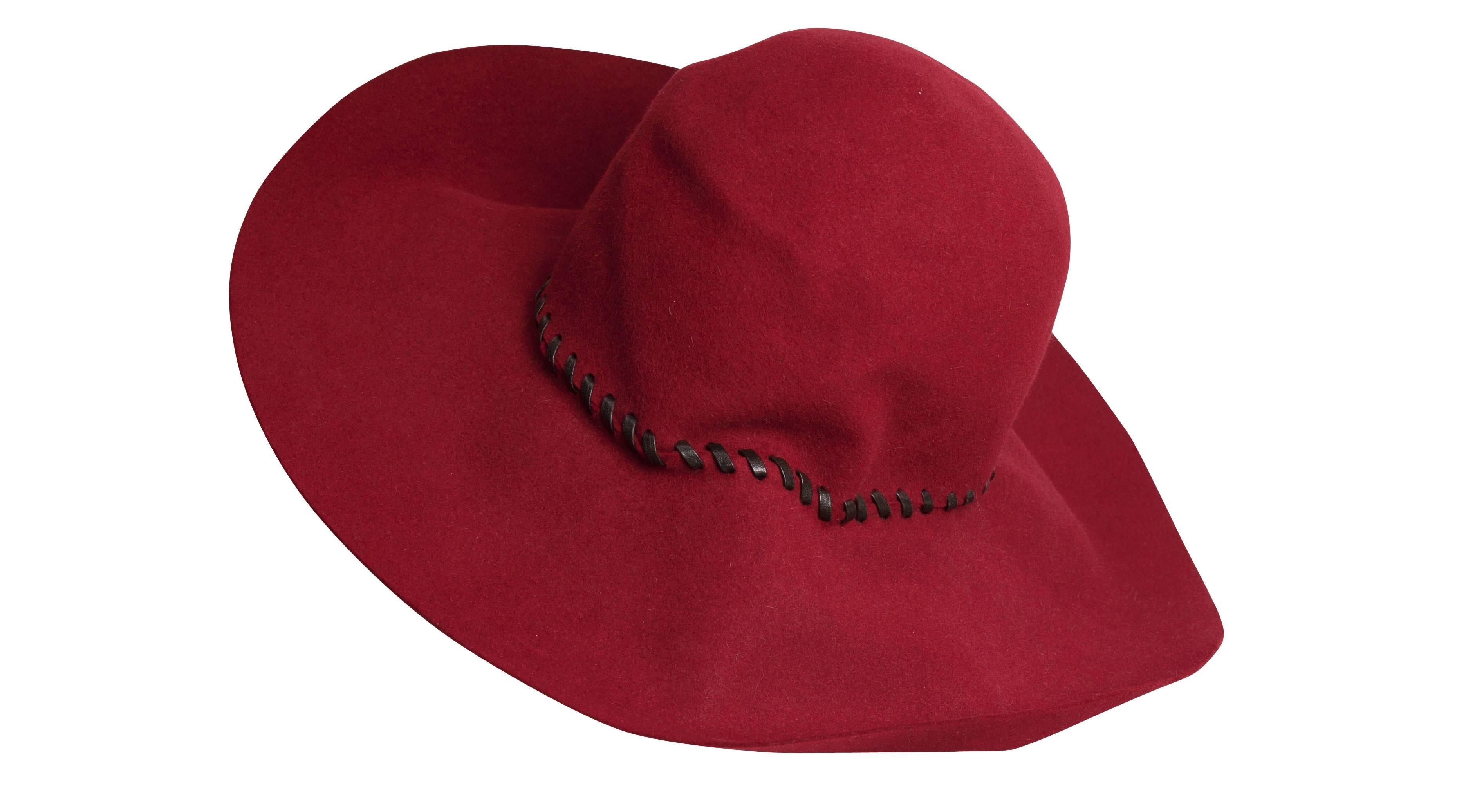 A 1970s Yves Saint Laurent Couture crimson floppy wide-brimmed felt hat, featured in the 1970 issue of L'officiel magazine. The hat features black leather diagonal stitching around the crown and a dark brown fabric interior seam. Excellent