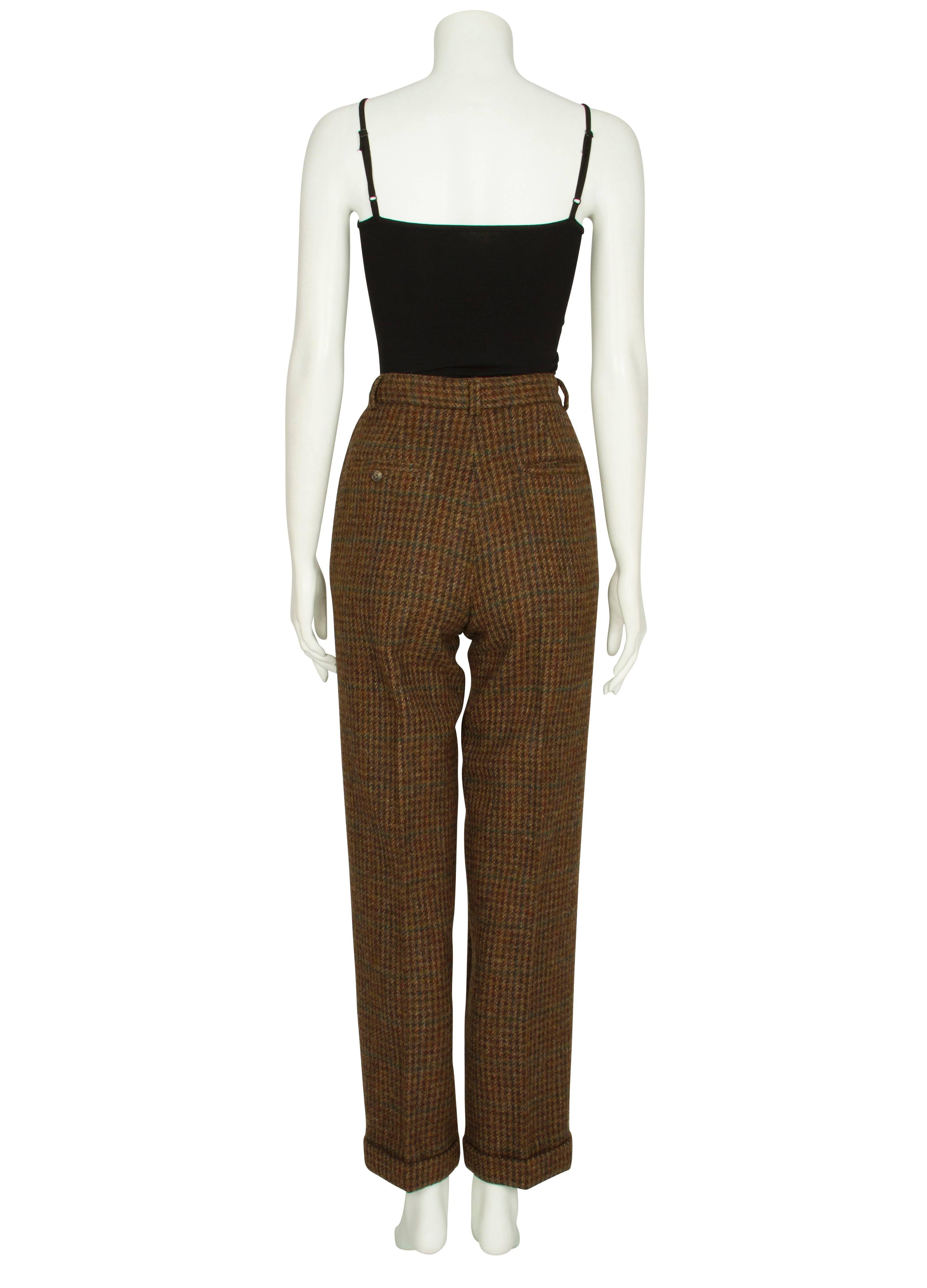 A pair of 1980s Ralph Lauren brown, green and burgundy houndstooth wool trousers. The heavy, textured trousers have a fitted high waist and wide pleated legs which gently taper at the ankle into wide turned-up cuffs. The trousers feature two deep
