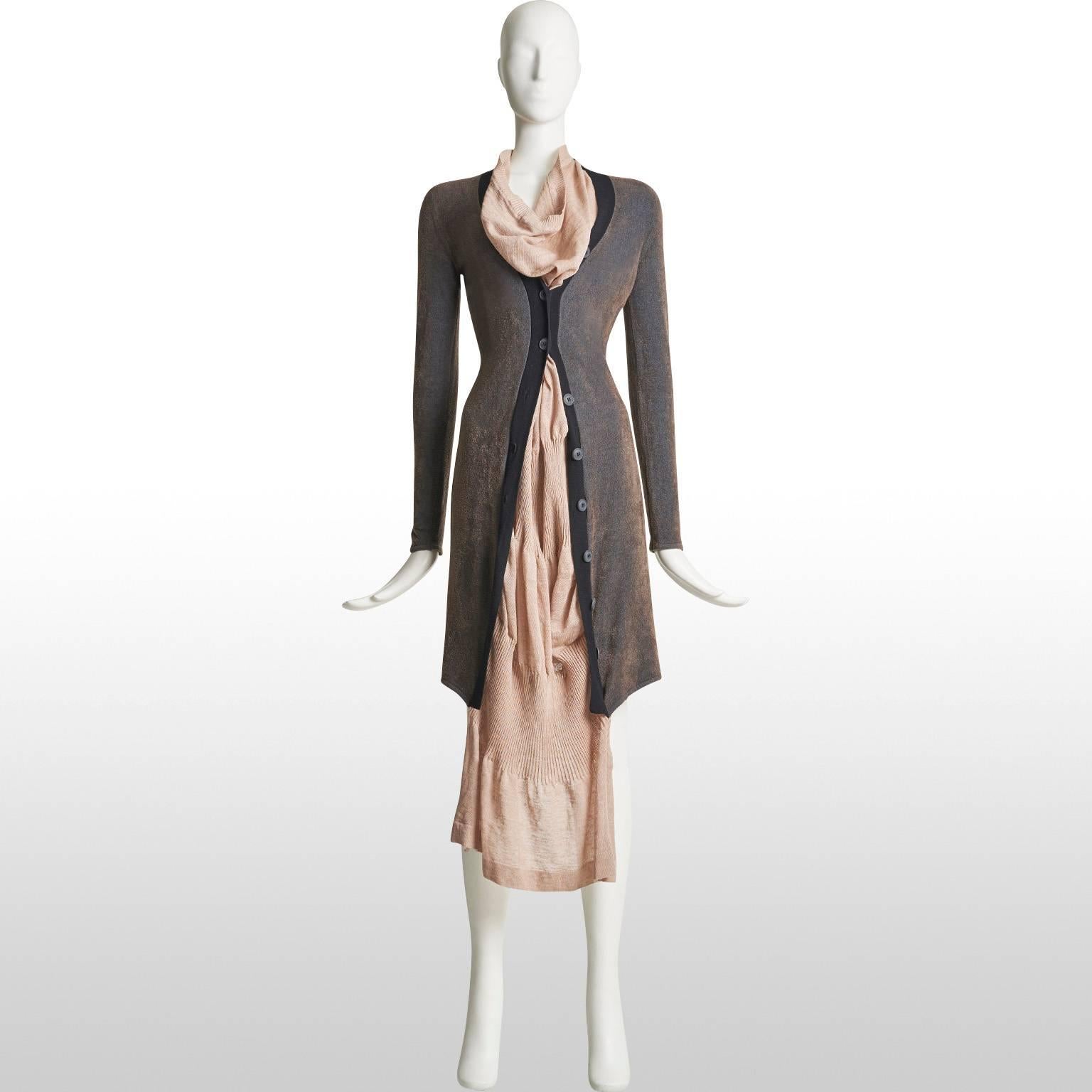 This is a cardigan dress by the designer Vivienne Westwood and is part of her Gold Label collection. The dress part of the piece is made out of linen and comes in a blush pink colour. The cardigan part is made out of a mixture of cashmere, viscose