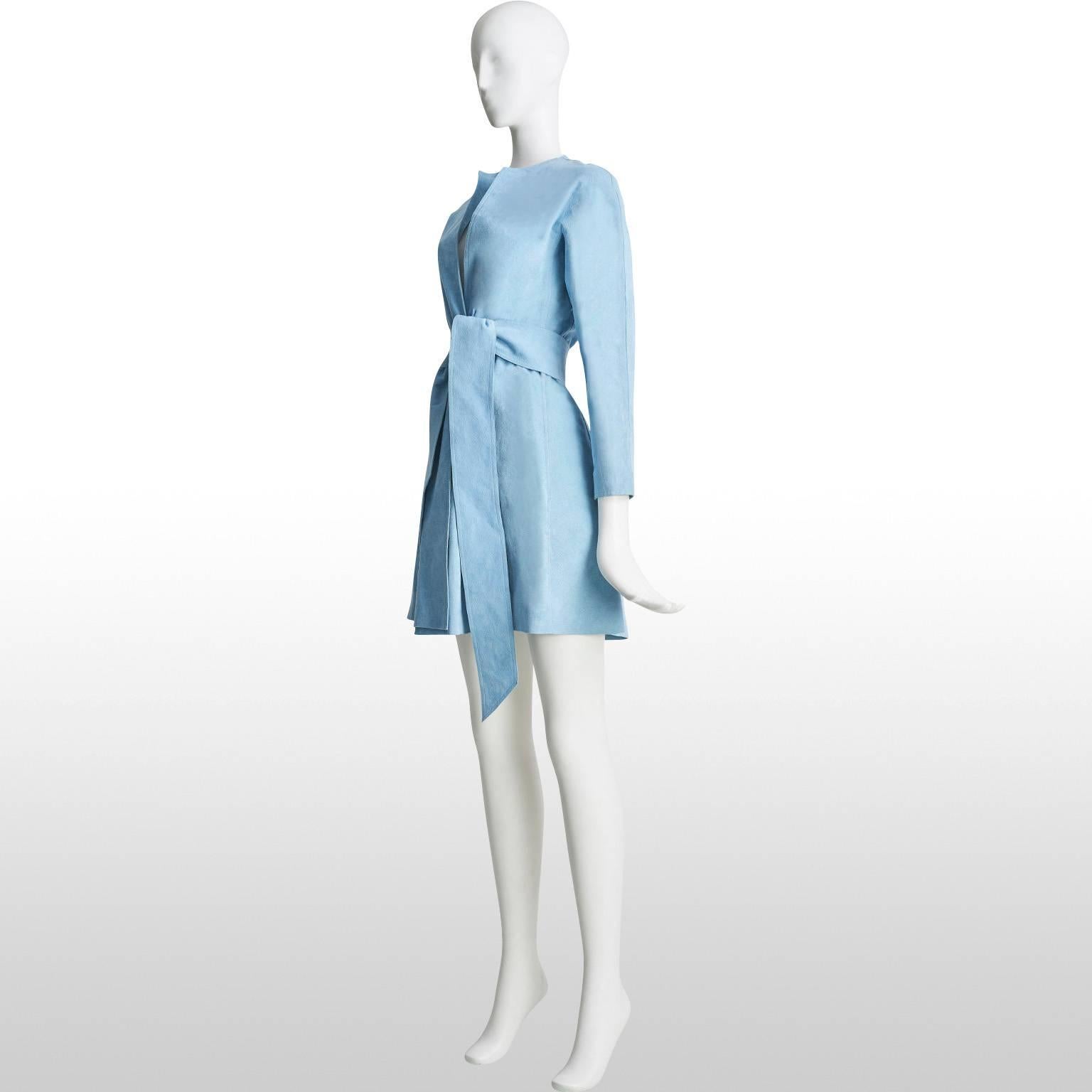 This gorgeous ultrasuede coat is Halston at his best. Not only is the colour a striking sky blue but the gathered waist with an accompanying sash belt make this mid length coat a true classic. It is perfect for the transitional weather in both