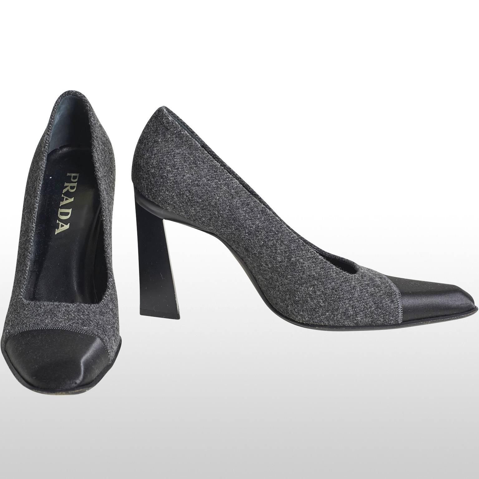 These are beautiful black and grey high heel shoes made by the design house Prada. The black part of the shoe is made out of satin where as the grey part of the shoe is made out of wool. The heel of the shoe is formed of a four inch trapezoid shape.