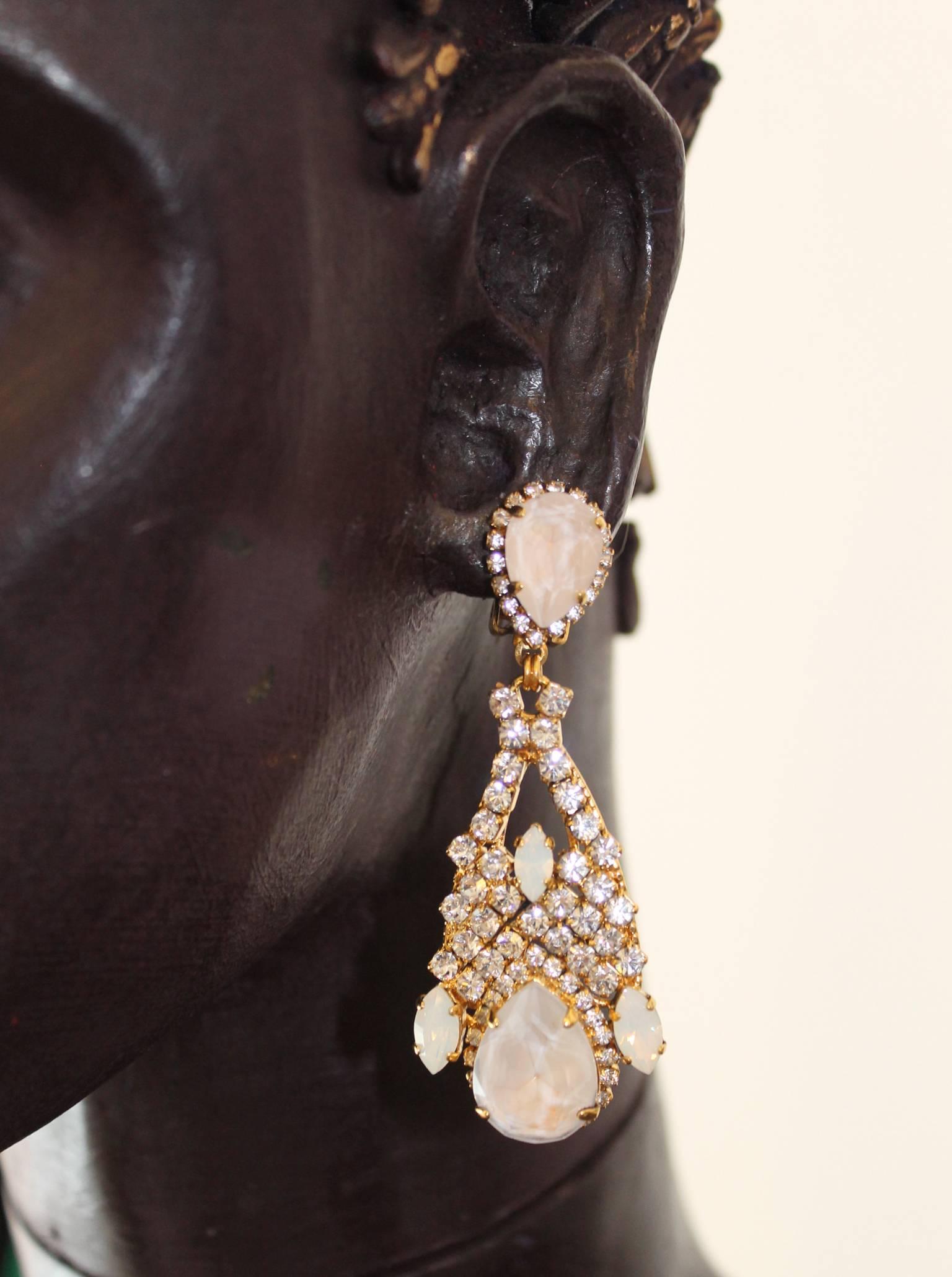 Elegant statement chandelier earrings by VICKISARGE; featuring both clear and hand-enamelled opaque white Swarovski crystals on a 23ct gold base, they are each individually handmade in the Belgravia studios under the eponymous Elizabeth St
