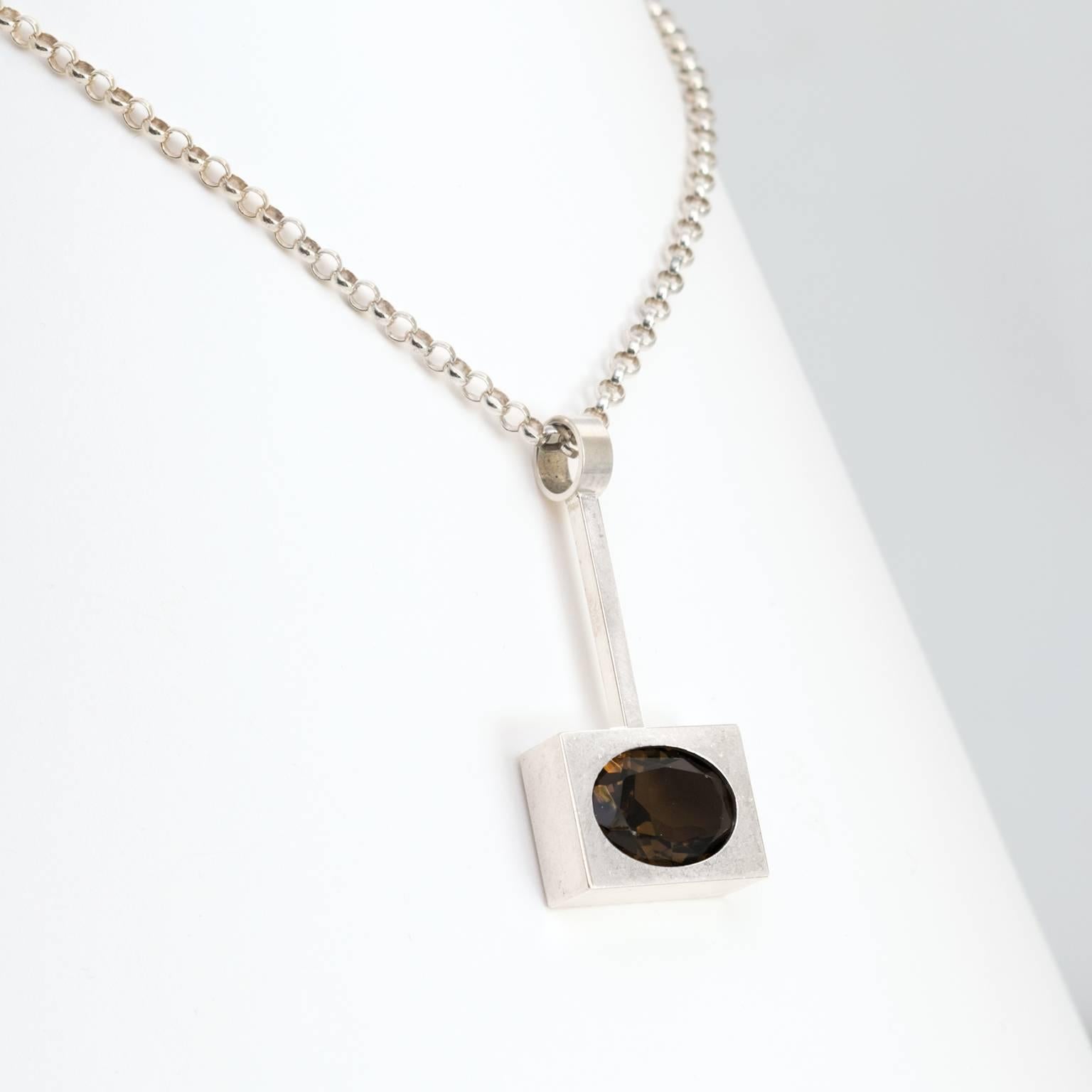 Silver Scandinavian Modern pendant with an inserted oval faceted smoky quartz stone. The chain is also silver. Designed by Kupitaan Kulta, Finland.
 
Chain length: 16