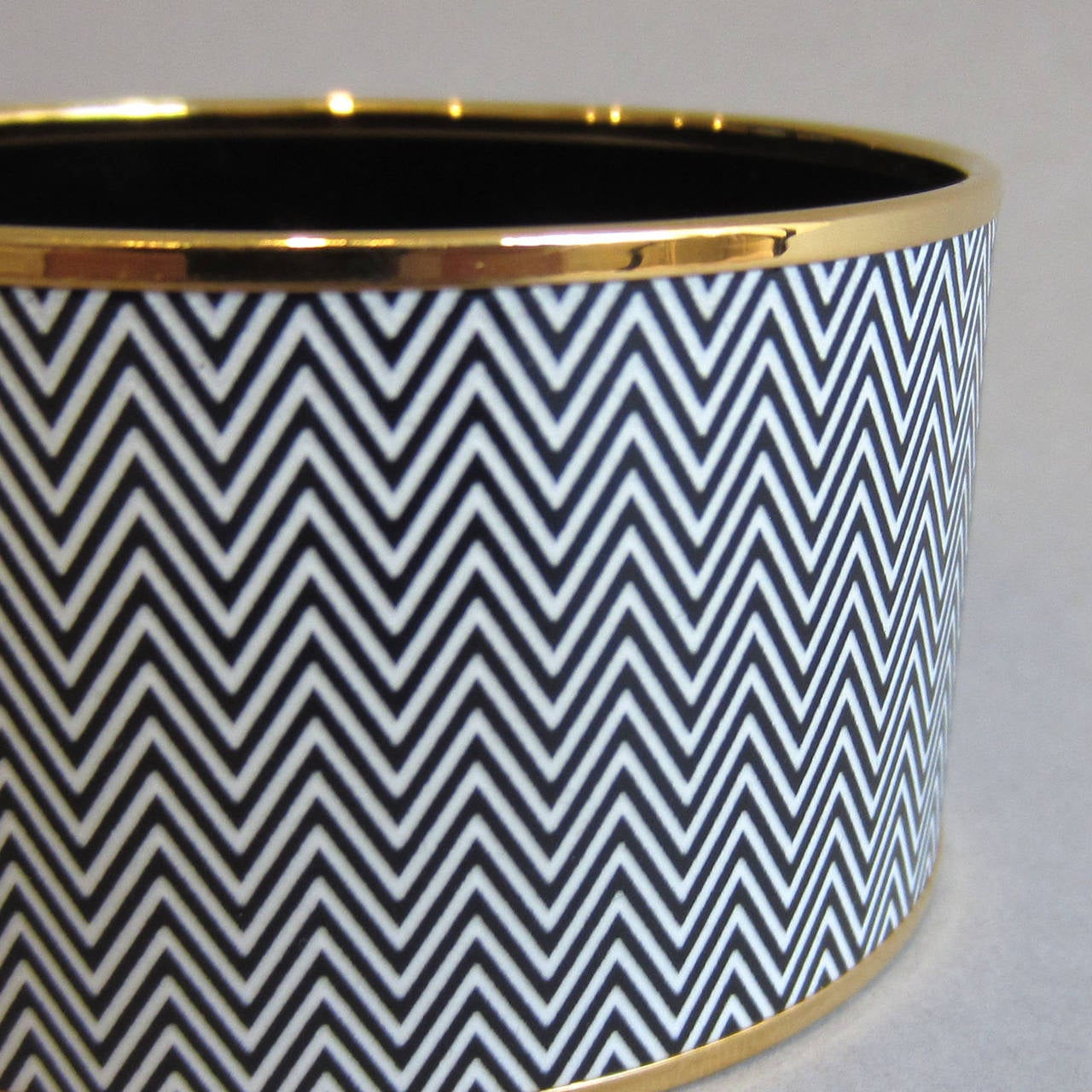 Beautiful and classic, this HERMES Bangle bracelet features a dark gray/black and white zig zag print. The print is accented with gold trim. The interior of the bracelet is black. Labeled Hermes. The original box and velvet pouch are included with