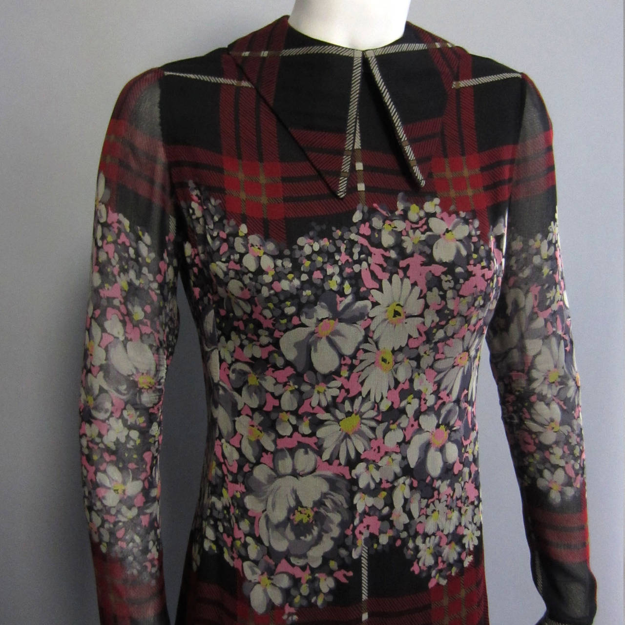 A beautiful 1970s piece from American designer JAMES GALANOS. This dress is made of silk chiffon. The oversized, burgundy and white plaid is set against a dark background. The graphic and linear plaid is broken up by an intricate, floral print