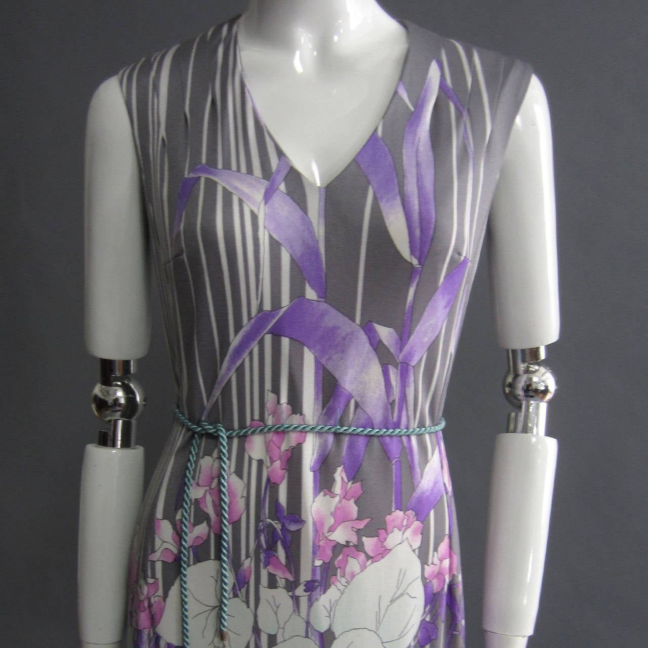 Grey, white, purple, pink and teal combine to create this intricate and modern floral print maxi dress. The print is localized and is the most ornate on the front; it clusters along the skirt with leaf details traveling up on the chest. The print is