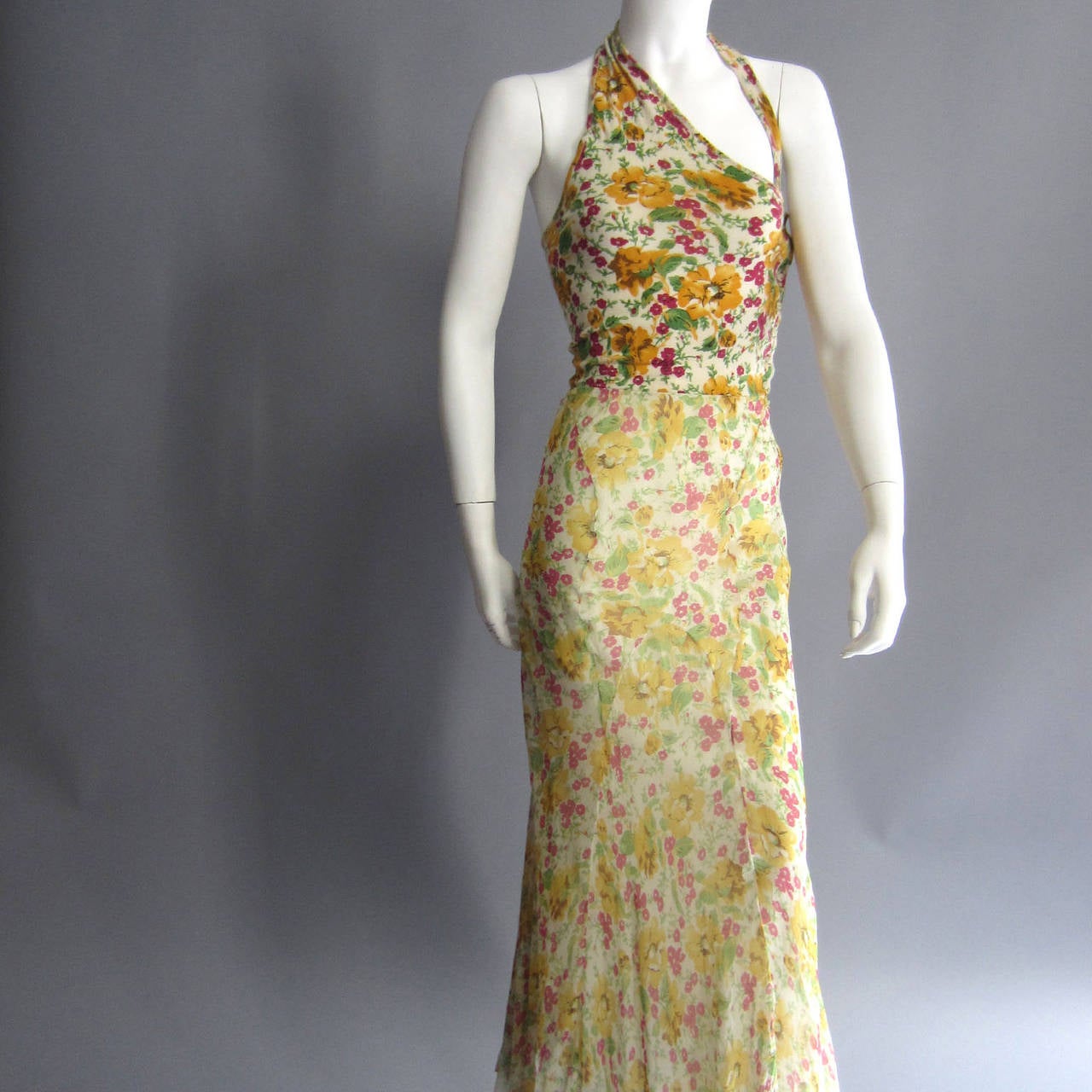 The gorgeous floral print of this gown is shared by the two separate fabrics. The top portion of the gown is made of cashmere; the one shoulder strap is secured with a covered button. From the waist down, the gown is made of silk chiffon. The bottom