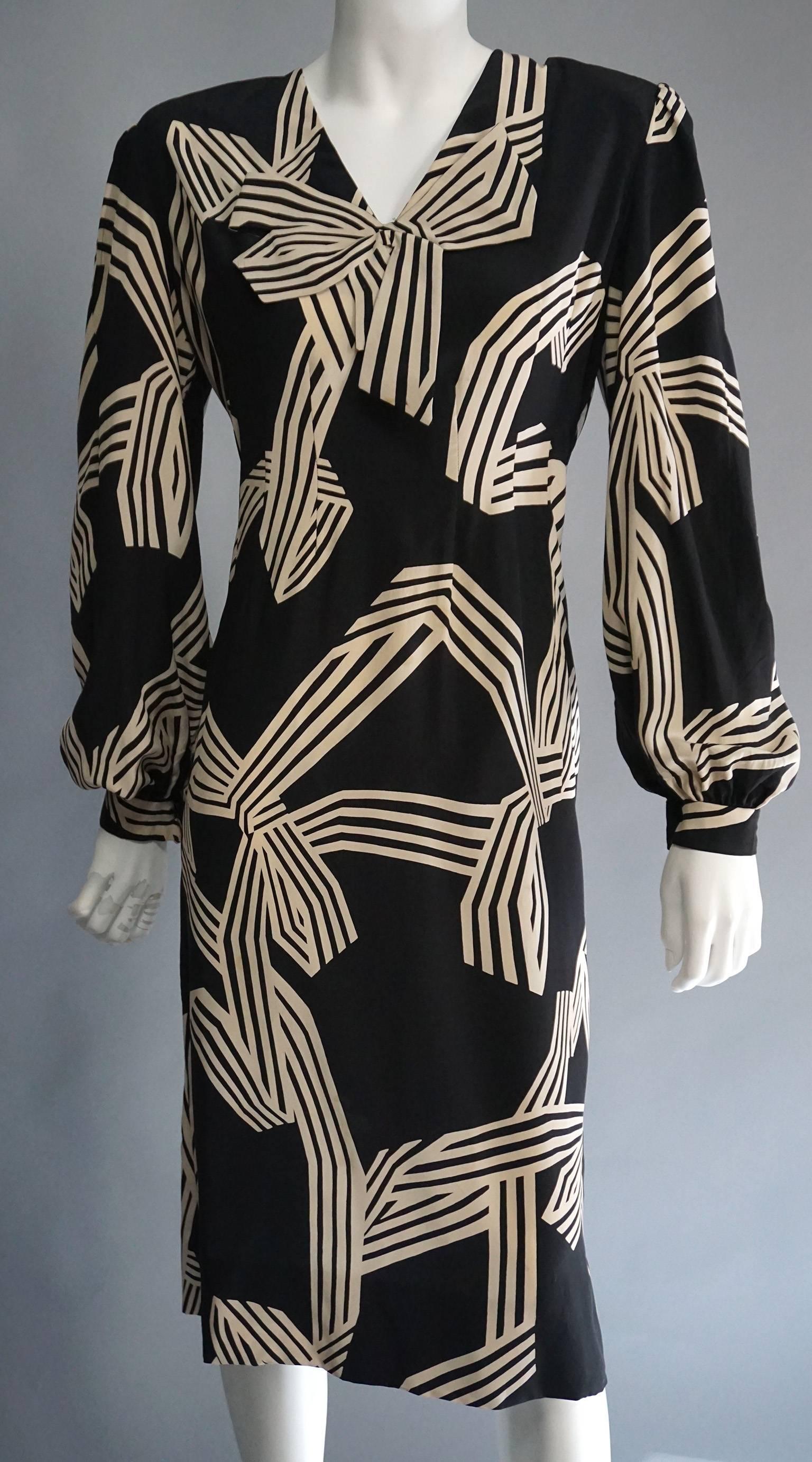 This graphic print PAULINE TRIGERE dress is classic, yet modern. The opposing colors create a vibrant, stripe print that references the fabric bow attached at the center of the neckline. The puff sleeves are capped with small cuffs with a single