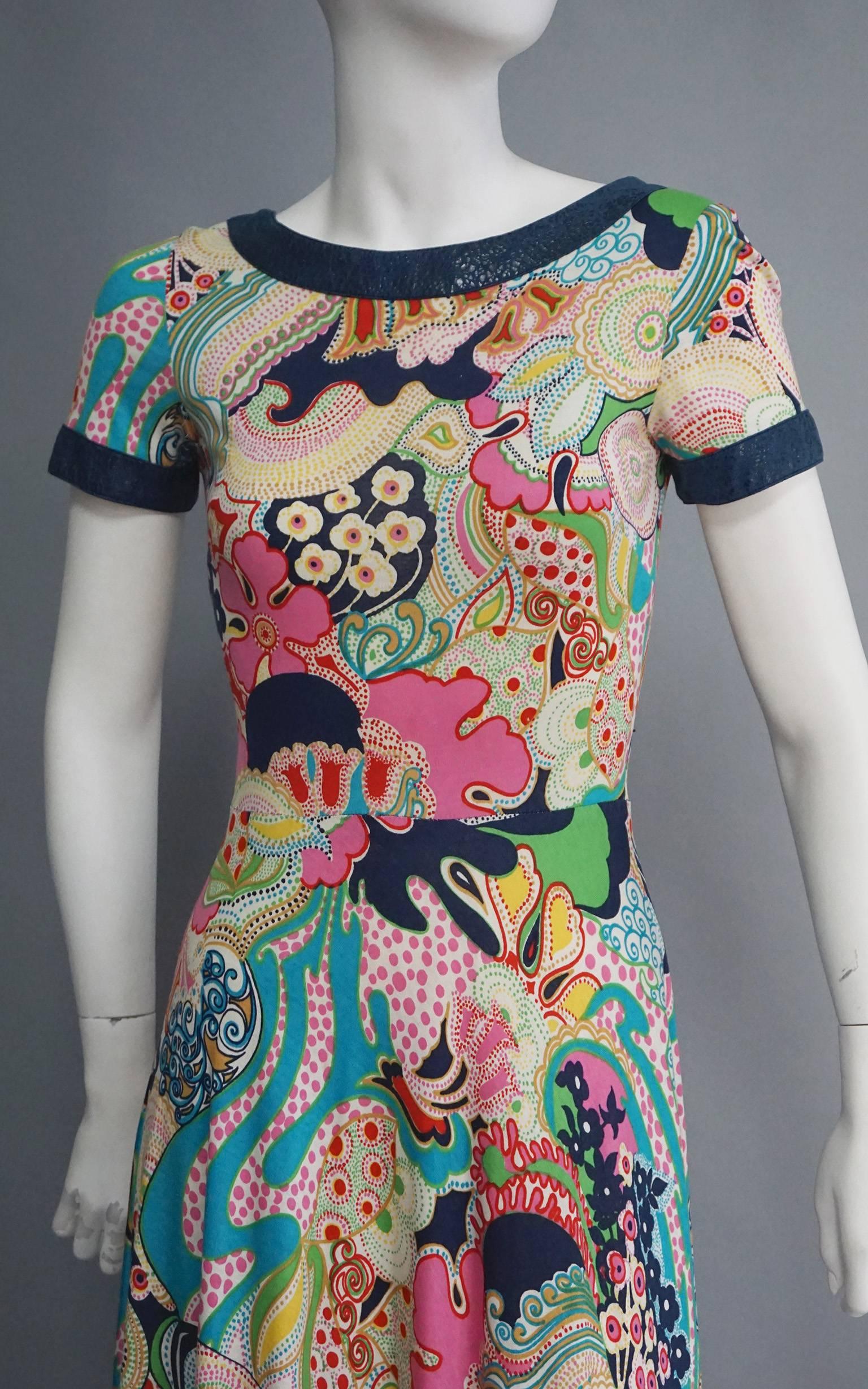 This LANVIN dress features a gorgeous psychedelic print. The colors cover the lightweight cotton fabric. It is fitted through the bodice, and then flares out over the hips into a full skirt. The neckline, sleeves and hem are all trimmed in a navy,
