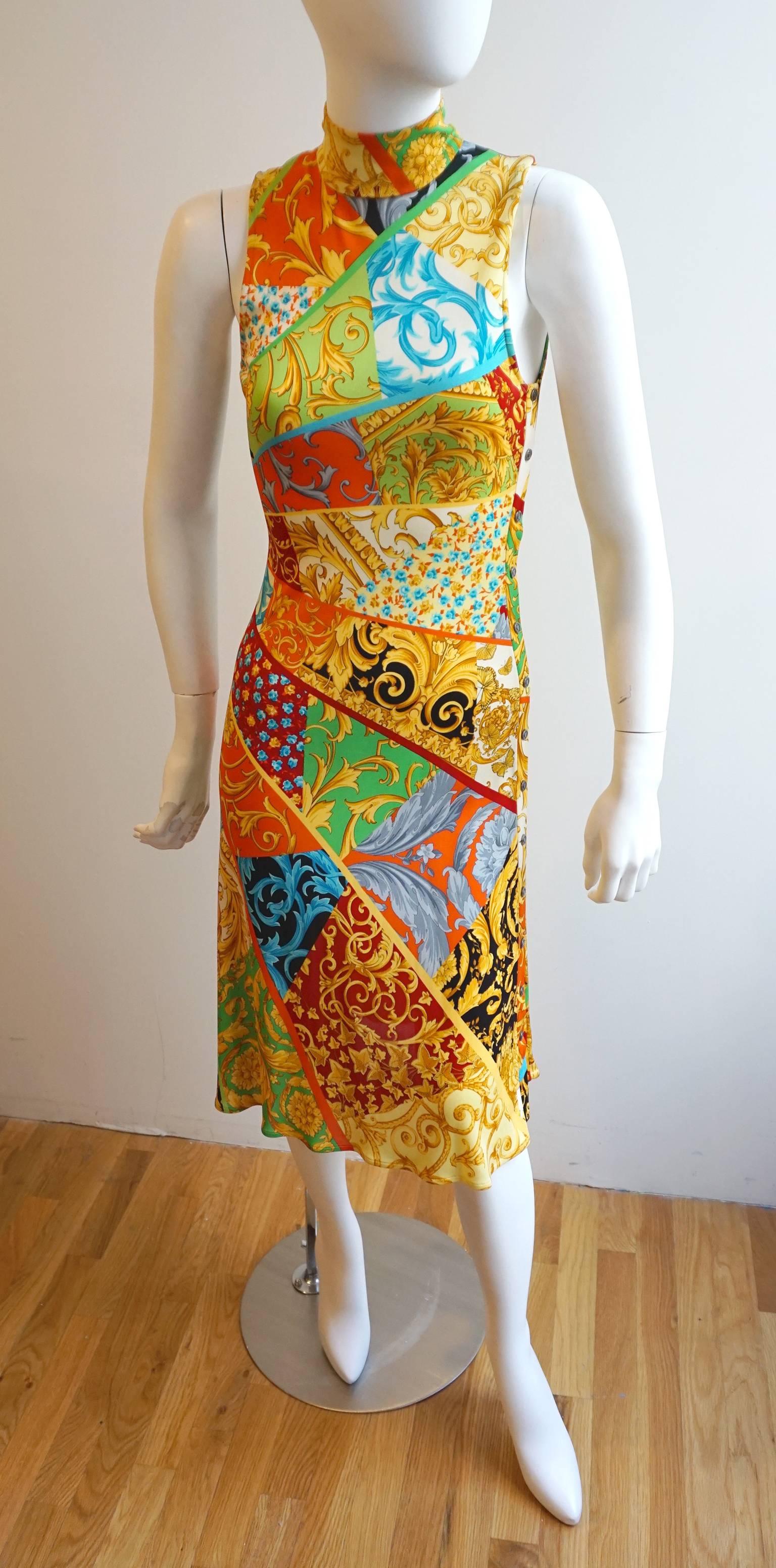 The print of this dressis quintessential VERSACE. The bold colors and prints are segmented and flare out from the right side of the waist. This highlights the body. There is a mock neck that is secured with double snaps on the back of the neck.