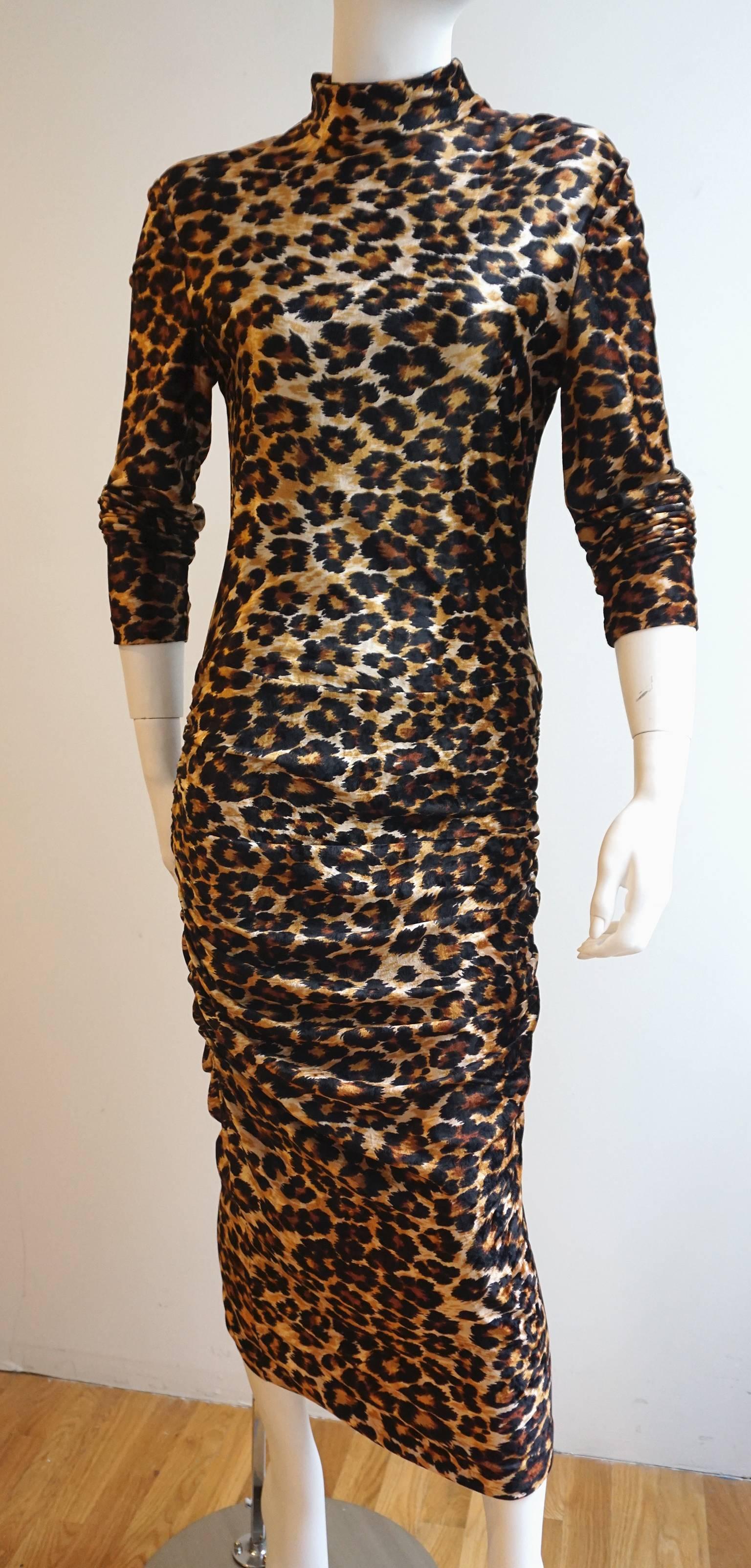 The soft, luxurious fabric features a bold and graphic leopard print. The fabric has a fair amount of stretch which accentuates the ruching along either side of the skirt. The mock neck and long sleeves cling to the body. There is a back zipper