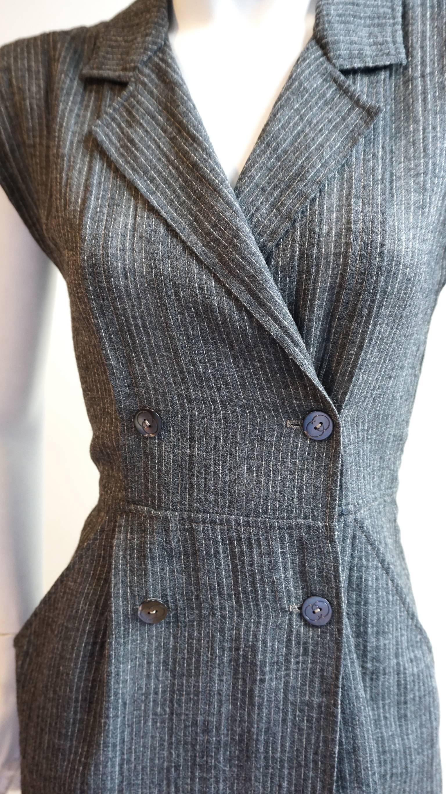 This GUCCI dress is made of high quality linen featuring a white on grey pinstripe. The sleeveless dress is accented with large lapels. The front is secured closed with the double breasted button closure. Hip pockets accentuate the waist. Unlined.