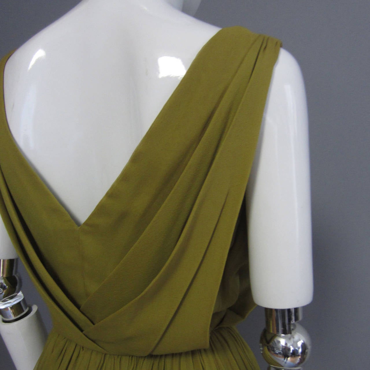 This dress showcases the beautiful and delicate uses of chiffon. The skirt is made up of various layers of olive green chiffon; the layers add volume and the small pleats create a visual texture. The top features draping at the neck. This is