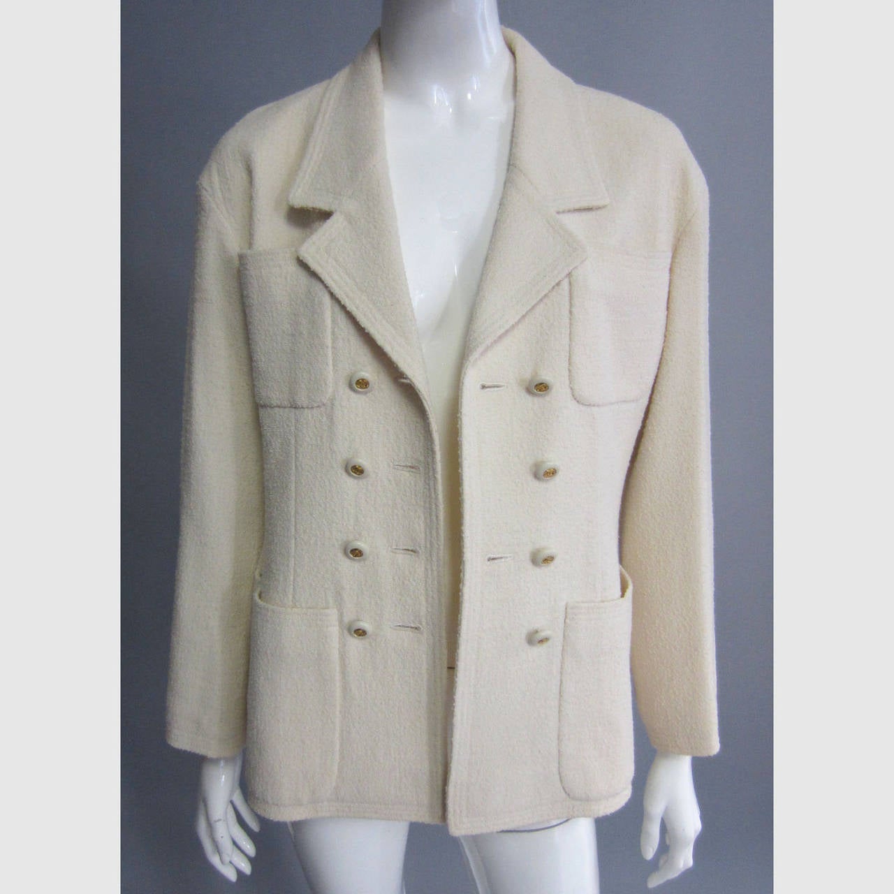 Classic CHANEL, this creme wool jacket features a double row of pockets on the front. The double breasted closure features a series of gold, CC logo buttons set in a matching creme. The lignin is silk with a white CC logo print throughout. The