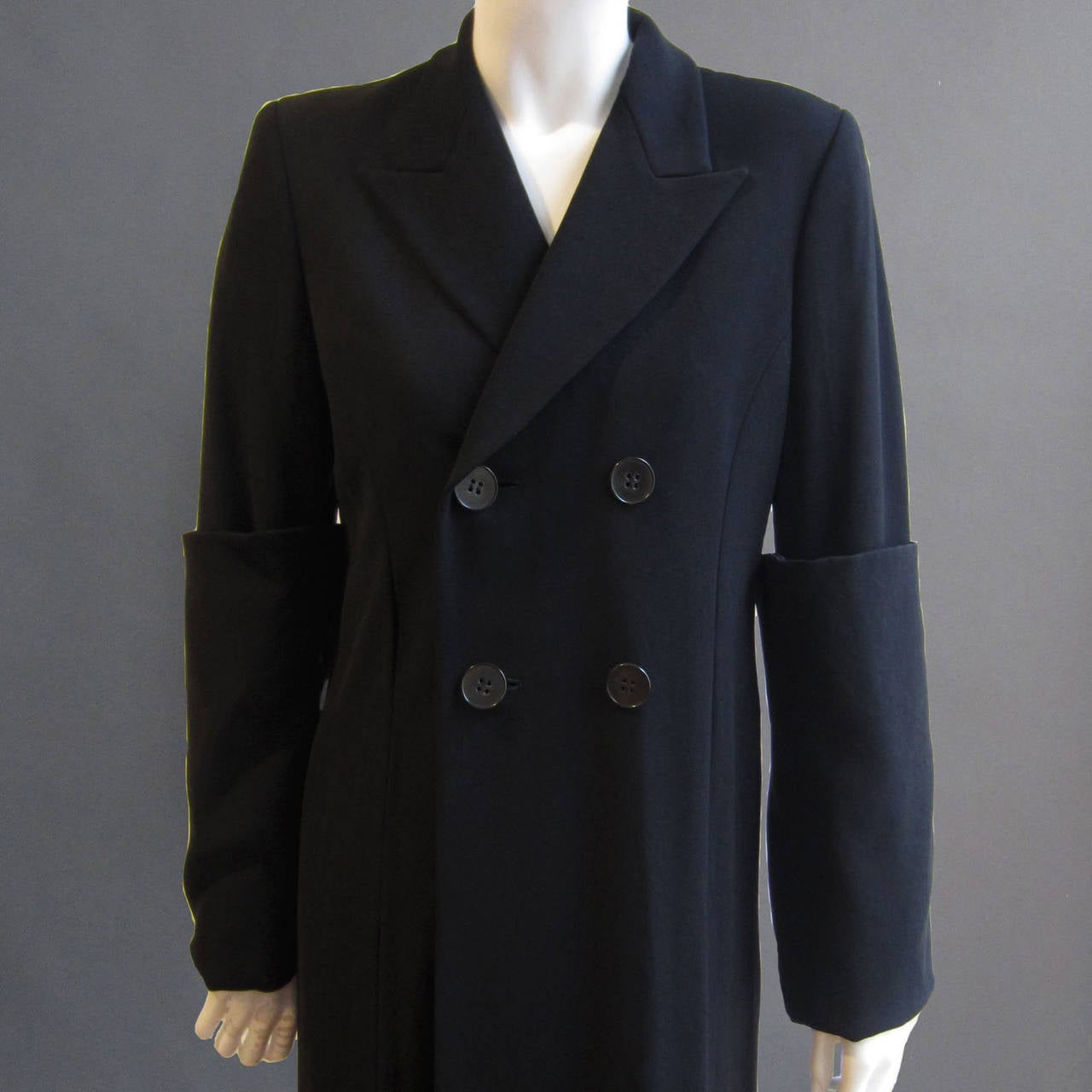 This 90s COMME DES GARCONS coat features a double breasted closure; a series of 4 buttons sit on the front chest. There is a beautiful lapel that accents the neckline. The genius feature of this coat is the exaggerated 13