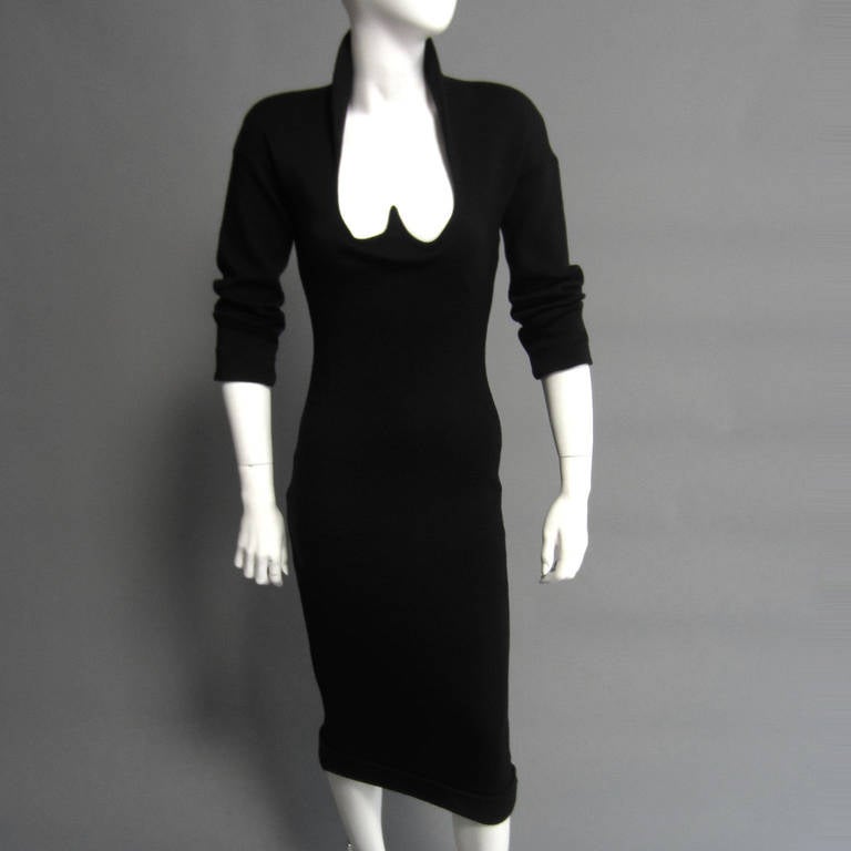 A classic, fitted dress from ROMEO GIGLI. The black knit forms to the body. The slight padding to the shoulders accentuated the collar detail. The heart shaped neckline is an iconic design detail. An interior elastic band around the bodice secures