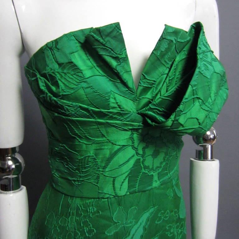 A stunning work of art from the legendary American designer, OSCAR DE LA RENTA. This gown is the epitome of OSCAR DE LA RENTA. The green, silk faille fabric is enhanced with a textured floral print, adding dimension. The strapless bodice is accented