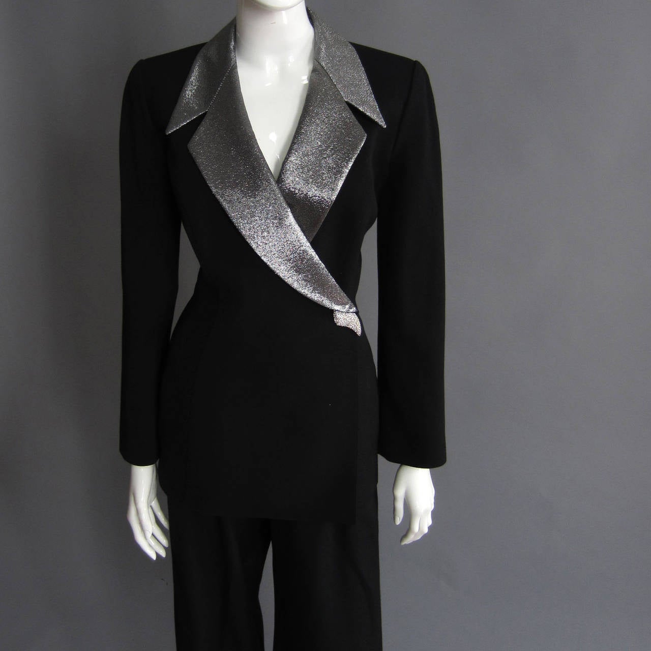 The THIERRY MUGLER version of a tuxedo, this pant suit is a masterpiece. The jacket is long, covered the hips. There is an interior snap closure, as the left side wraps over the right. There are two hidden snaps underneath the rhinestone closure