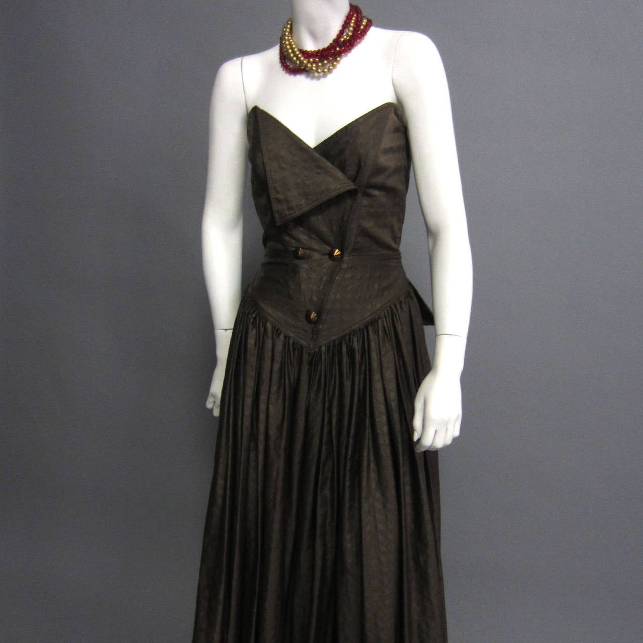 There are several, stunning details to this BALMAIN cocktail dress. The lightweight fabric is covered in a brown on brown houndstooth print; a shiny brown and a dull brown intersect to create the faint print. The bodice is made of two, overlapping