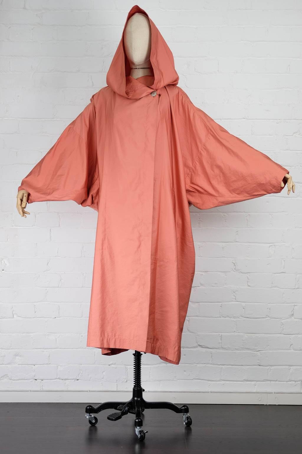 Salmon light hooded coat  circa early 1980s  featuring long sleeves, long length, side pockets and a button fastening on inside and out. 

Total Lenght 117cm
Waist 160cm
Bust 162cm
Shoulders 85cm
Sleeve 60cm

