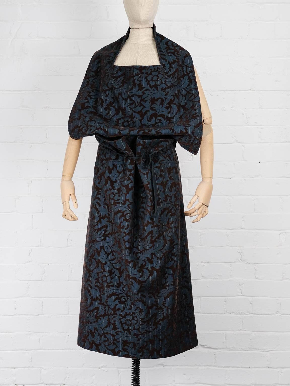 1996 Blue wool floral flock halterneck dress,  featuring an open back, a back tie fastening, a mid-calf length, a sleeveless design, a draped design, an elasticated waistband with a drawstring fastening and a contrasting floral flock print.

Total