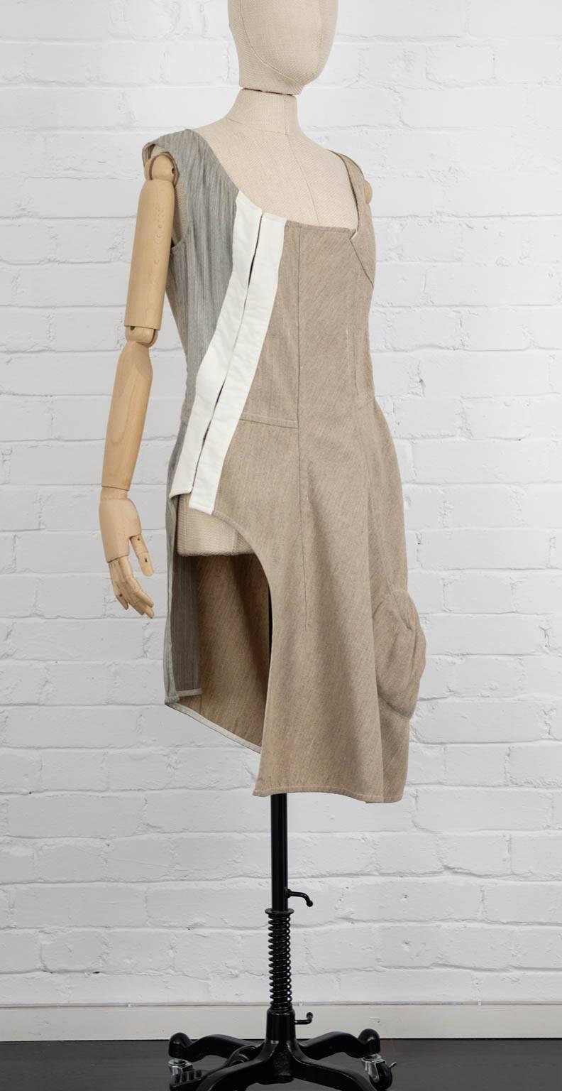 Sand linen and wool blend asymmetrical dress from Comme Des Garçons Vintage featuring a square neck, a sleeveless design, a fitted waist, a side slit, an asymmetric style, a knee length, padded detailing. Fall 1998