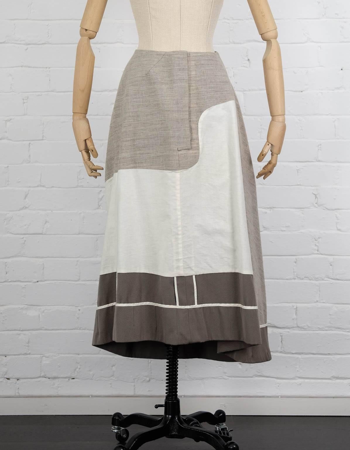 Khaki, grey and brown wool reversible skirt from Comme Des Garçons Vintage featuring a front hook and eye fastening, an a-line shape, a pleated design, a flared style and an asymmetric hem. Fall 1998