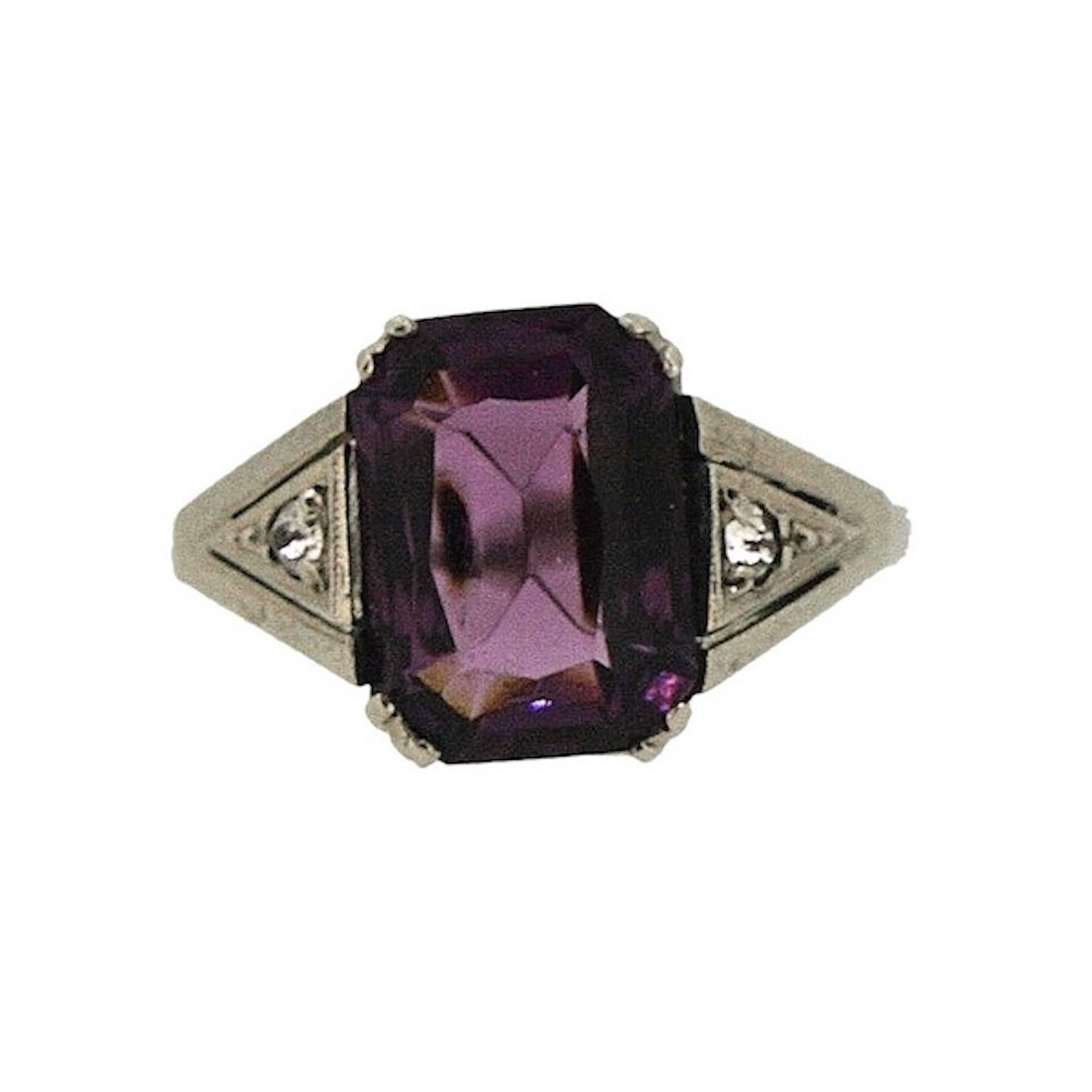 Elegant and evocative, this beautiful ring was created in the 1920s and is, most likely, French. 
Condition Report:
Excellent
The Details...
This silver tone ring features a central emerald cut purple glass stone, claw set in a raised mount.