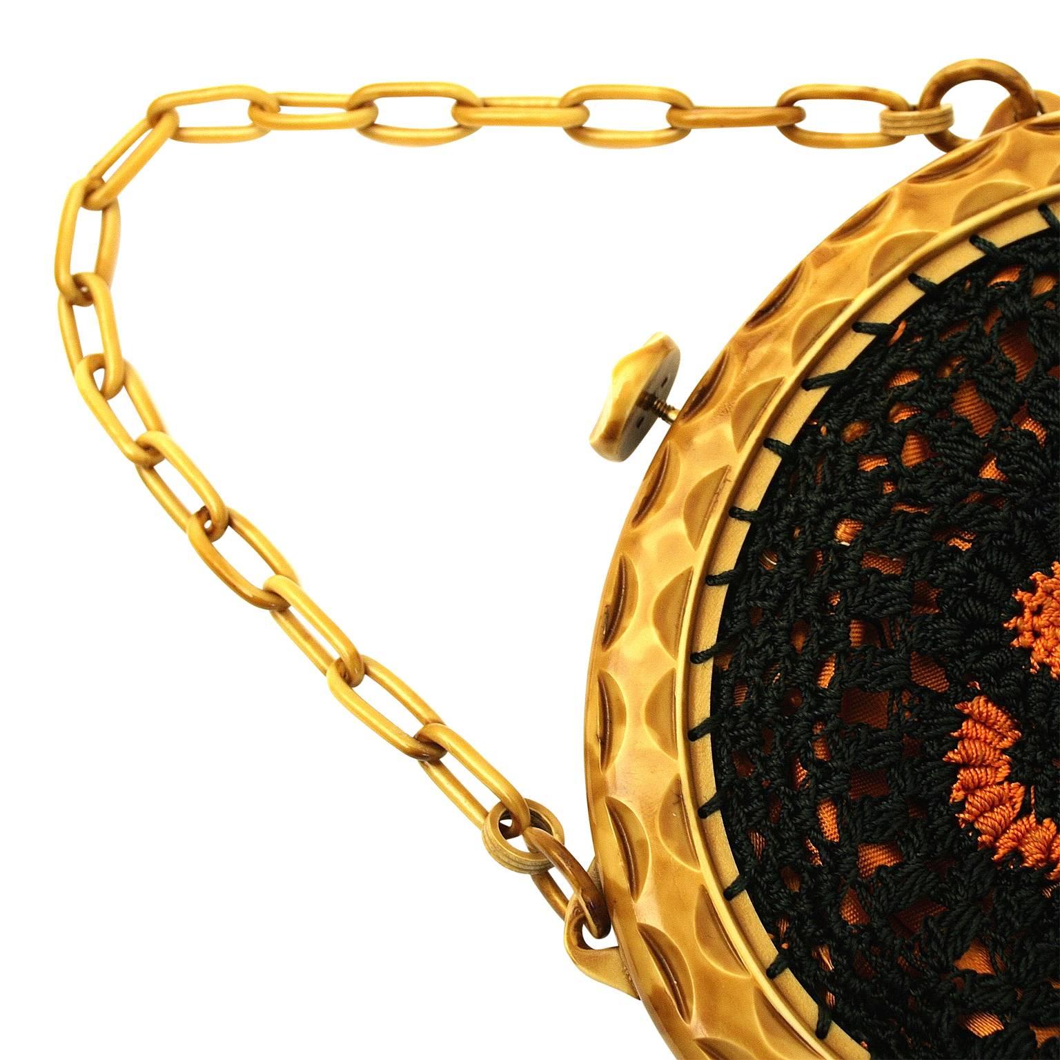 This pretty and evocative bag was created in the 1930s. 
Condition Report:
Excellent
The Details...
This elegant bag is crocheted in orange and blue thread. It features a celluloid frame and celluloid chain handle. The bag opens with a push button