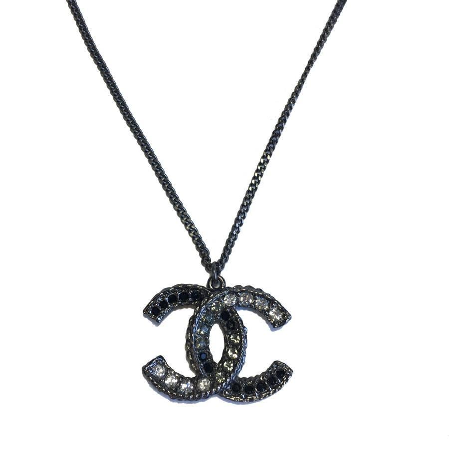 CHANEL necklace with the Iconic 'CC' logo pendant in ruthenium (darker Sliver Tone metal) and black and white Rhinestones. The CC has one side in Rhinestones and the other in black resin. 
Signed on the back of the Necklace with a metal signature