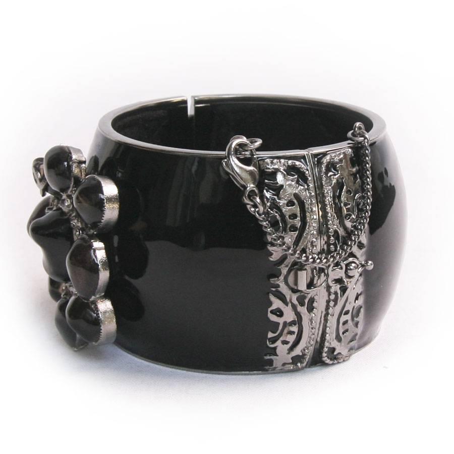 Beautiful Chanel cuff, black enamel, and surmounted by an imposing clear dark topaz color glass gemstone. It is made of aged silver metal. The interior is padded in a shiny black fabric. It closes with a magnet and a safety clasp.

Cuff dimension: