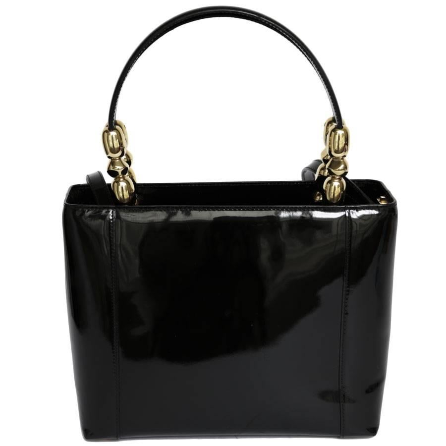 Lady Dior bag in black patent leather from Maison Christian Dior. Gold jewelry. Zip closure. Two handles for hand carrying and a removable shoulder strap for shoulder carrying. The inside is in monogram black fabric with 2 patch pockets (one is