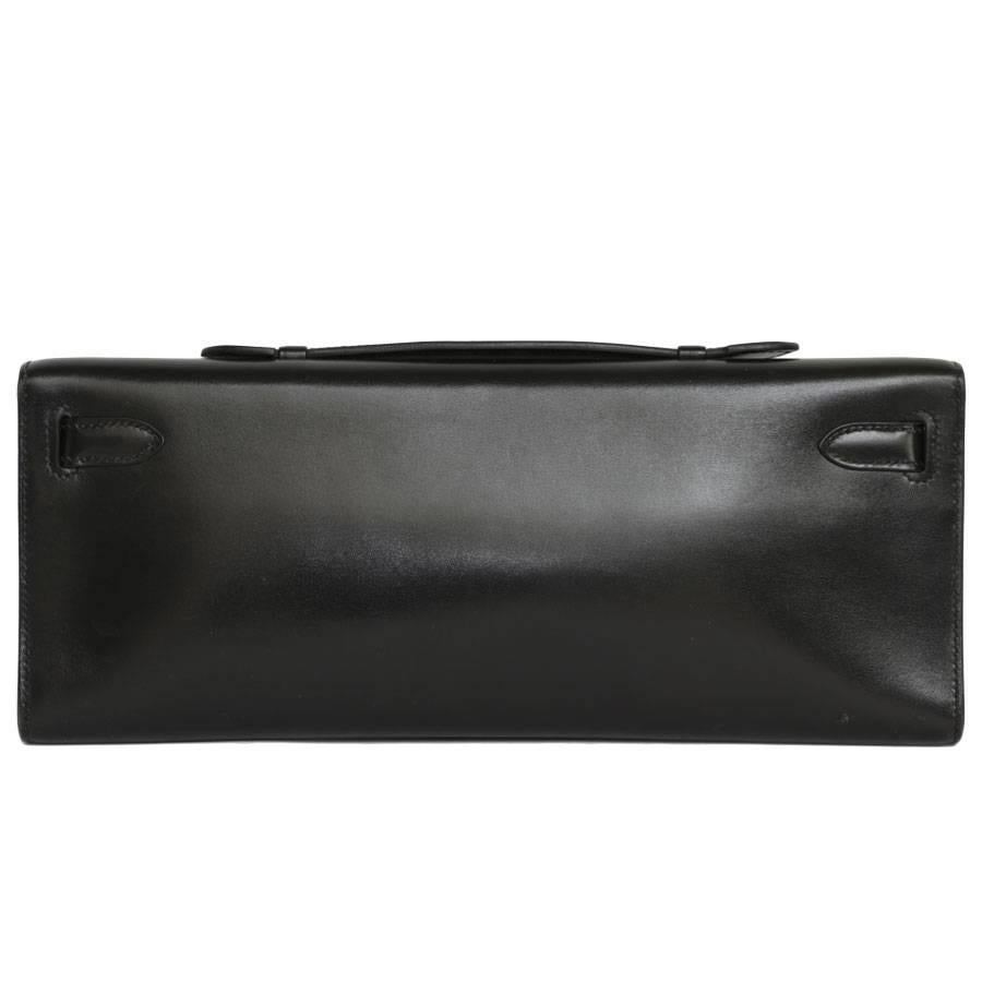 'Kelly cut' pochette in black box leather from Maison Hermès. Palladium silver jewelry (micro scratched). The interior is in grained leather with a small patch pocket. Stamp M in a square (= 2009). In excellent condition.