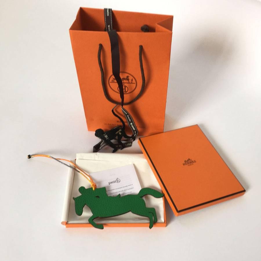 Beautiful HERMES charm horse and jockey, model H small, green leather and grained brown. Link in silk twill.

Brand HERMES on grained gold leather.

Delivered in its box HERMES with its link embellished with a charm monkey in black leather. All in a