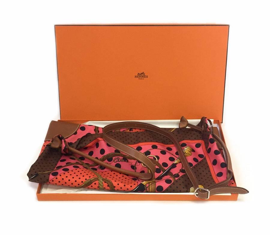 HERMES 'Silky City' silk Bag in multicolored silk with predominantly orange color and Gold Barénia Calfskin with white stitching. Silver plated hardware, 
Small zippered pocket inside. Closure with bell link. 

Worn shoulder strap. It comes from