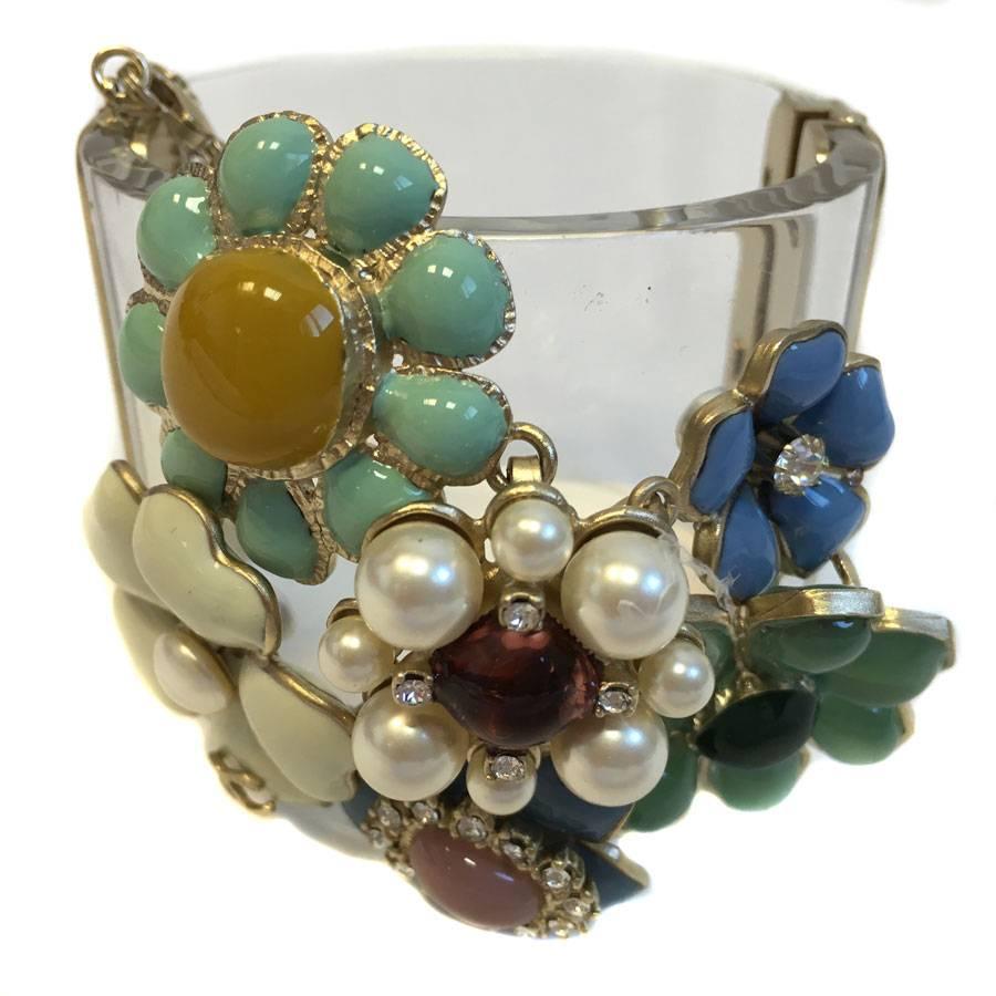 Superb piece! Collector CHANEL cuff  in transparent plexi decorated with flowers in multiple colors glass paste (purple, jade, blue, green, off-white, garnet, ...), Swarovski rhinestones and a hammered gilt metal CC.
Pushed clasp with a pale gilt