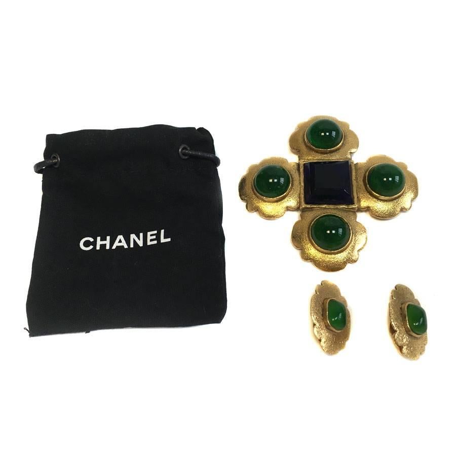 Very beautiful vintage CHANEL parure composed of a brooch and a pair of clip-on earrings

The brooch is in gilt metal in the shape of a cross decorated with 4 round stones in emerald molten paste and a square stone of sapphire color.

The clip-on