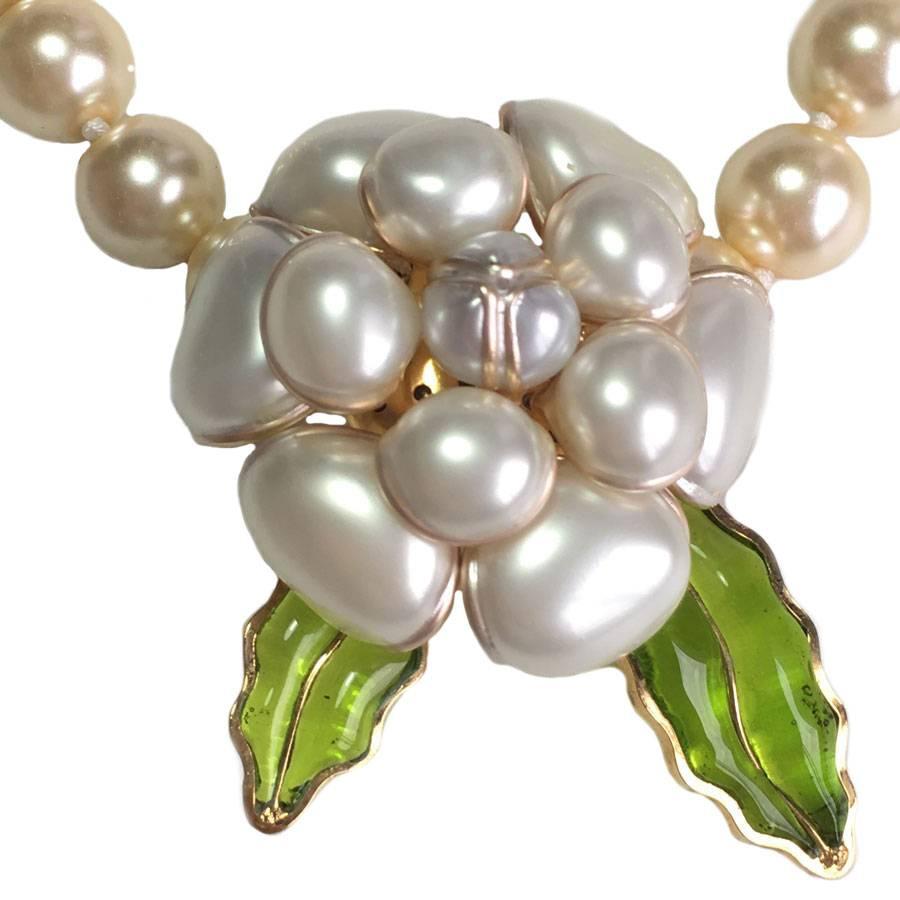 Superb MARGUERITE DE VALOIS necklace camellia in glass pearls and leaf in green molten glass. Hook clasp in golden plated metal.

 The Maison Marguerite de Valois makes its jewels in its Parisian workshops. It uses an ancestral technique for the
