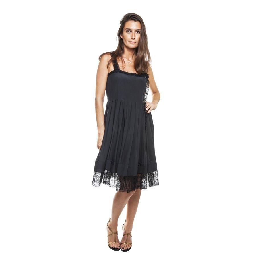 Chanel cocktail pleated wrap dress in black fluid silk. Lined with light lace, it is suitable for an elegant evening. 

There are 4 silver matt plated metal with dark red cabochons buttons that adorn the bust. 

The shoulder straps are also made of