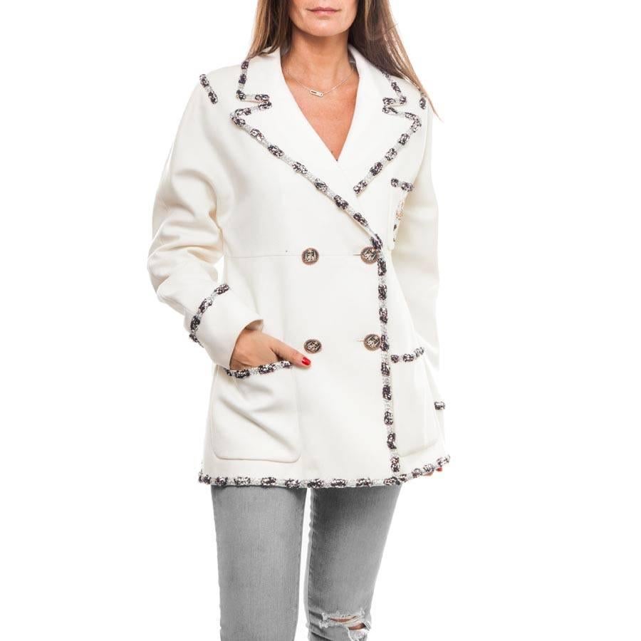 Chanel jacket, collection 'Paris Bombay' in white wool lined with white monogram silk. Comes from press sales.

It has a patch pocket with an embroidered patch, as well as two pockets. 

A silver, navy and red braid draws the jacket, the pockets and