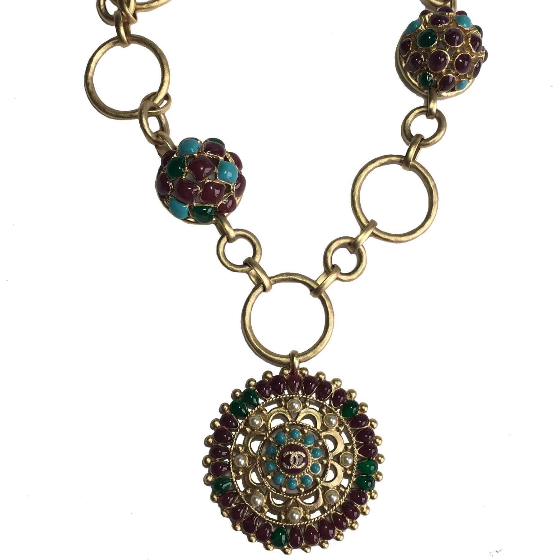 Superb Chanel necklace from the Métiers d'Arts 'Paris-Bombay' collection. Chain and pendant made of gilded matt gold, pearls and molten glass burgundy, turquoise and green. Two small chains end the collar at the clasp.

Dimensions: total length at