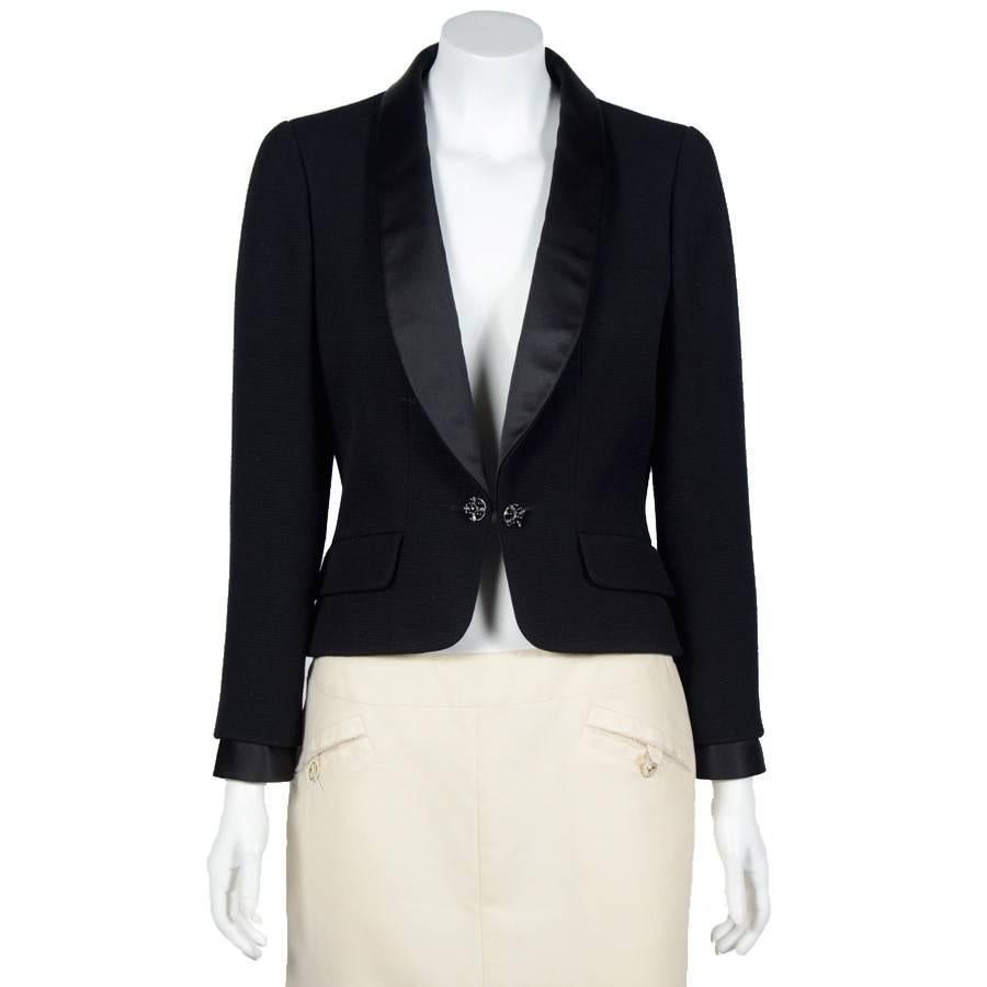 Chanel short black tuxedo jacket, coming from ready-to-wear autumn 2006. The jacket is made of wool, the collar and sleeve finish are made of thick silk. It is equipped with four precious metal buttons and inlaid black stones on each handle. 
It