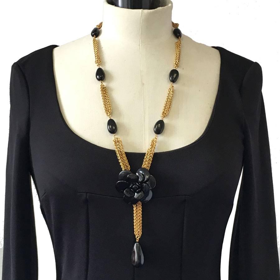 Couture!! CHANEL pendant necklace with a camellia in black molten glass and a gilded metal chain decorated with oval beads in black molten glass.

Delivered in its Chanel box 
